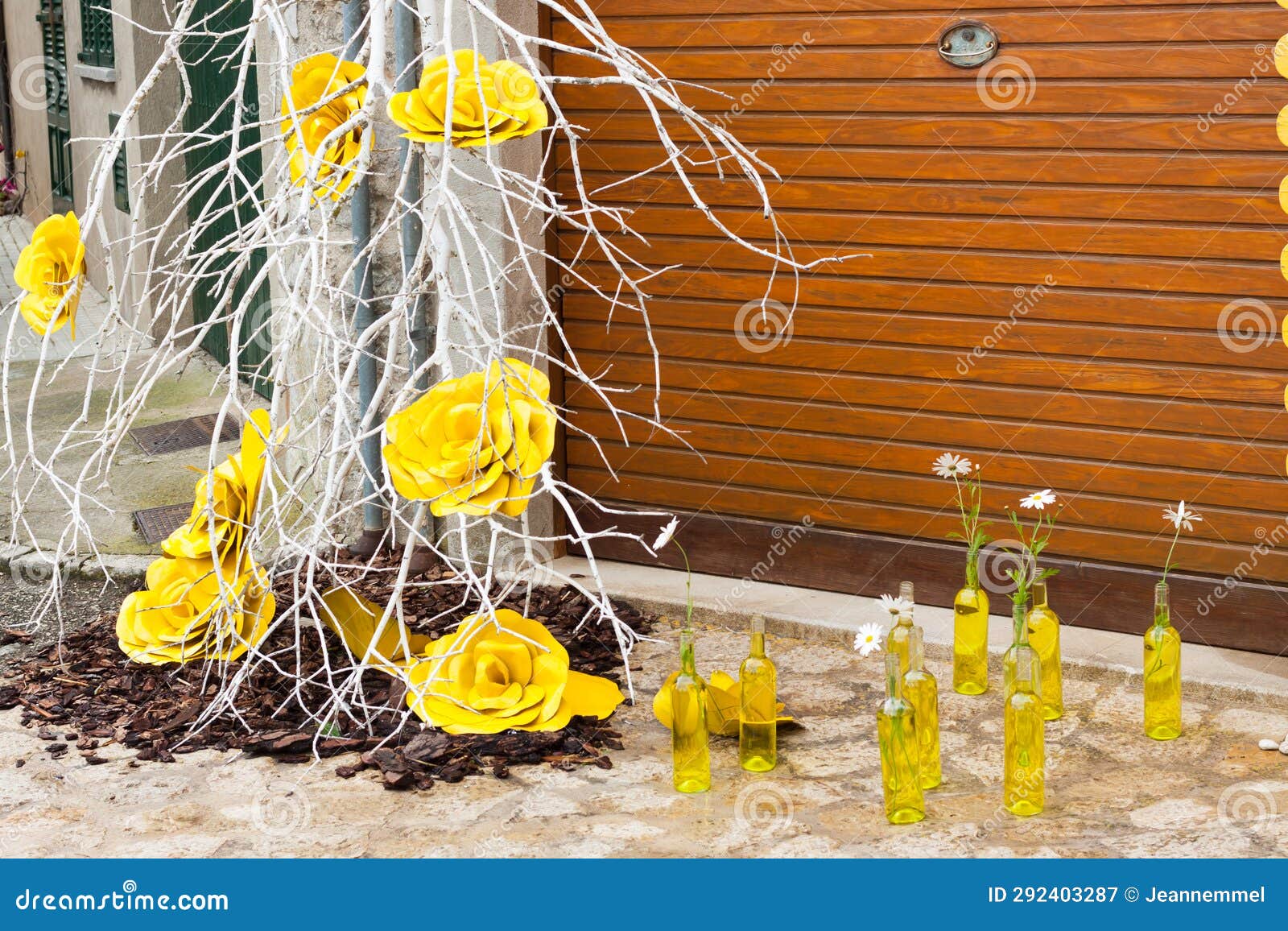 branch with yellow roses and some yellow bottles with daisies on the floor on 