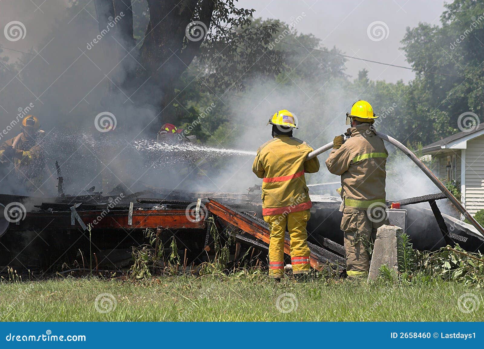 Brandmän som ut sätter husbrand. Brandmän som sprejar vatten på brännskada ut, house eller returnerar.