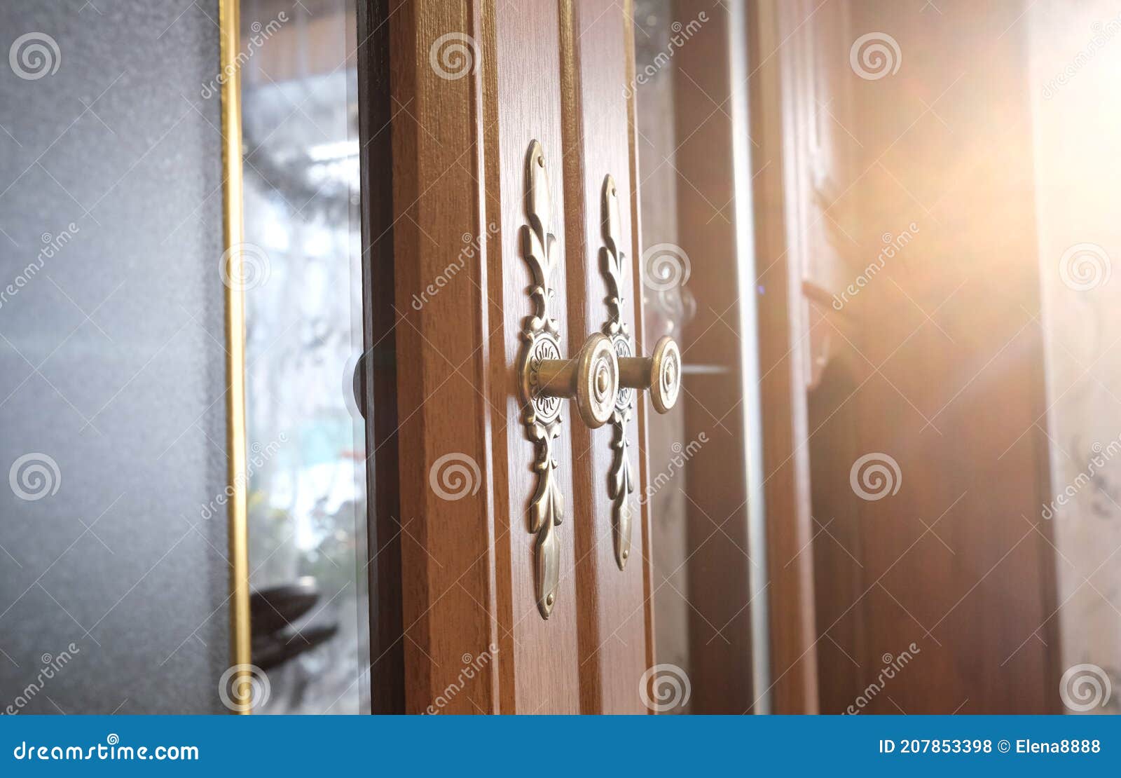 brass door with glass inserts and handles with ornate escutcheons on a wooden cabinet , close up, authentic interior home