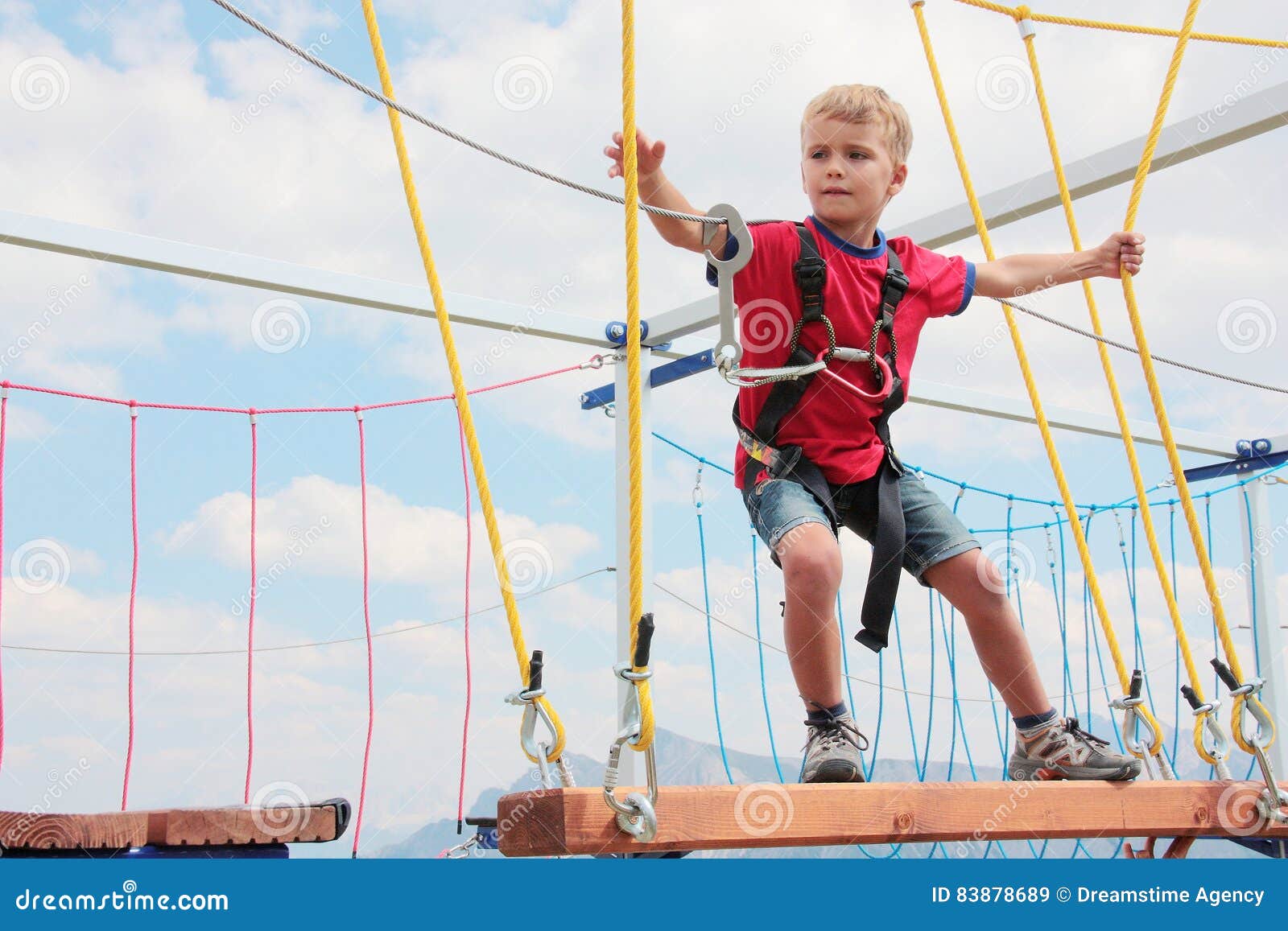 brave blond hair kid playing rope course outdoor