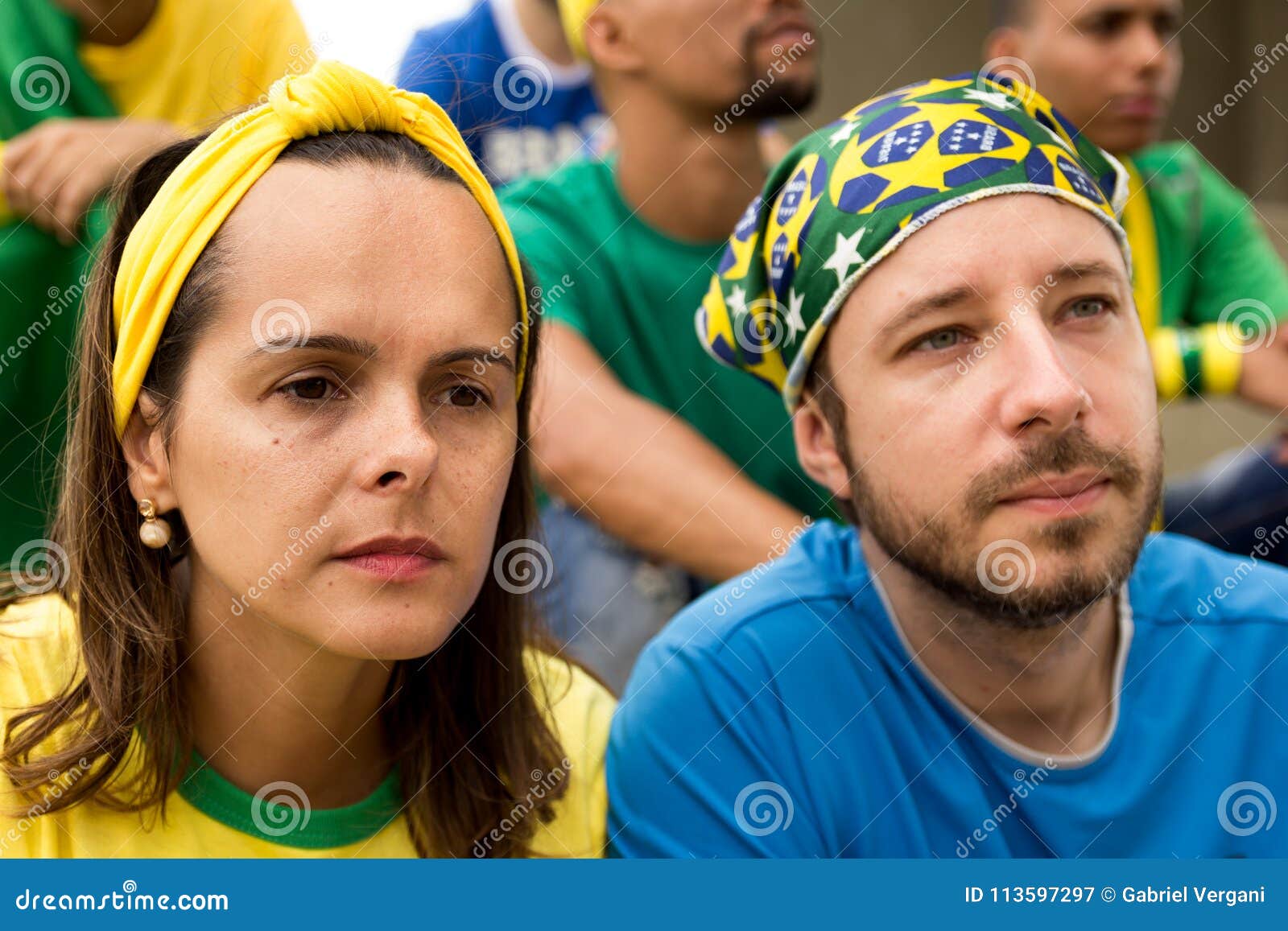 group of fans watching a match and cheering brazilian team.