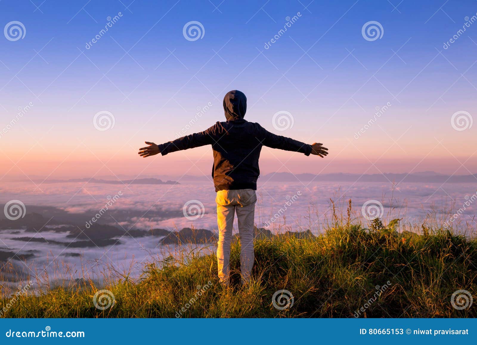 Brazos del hombre encima de la montaña con la niebla que fluye y hermoso abiertos. Brazos abiertos del hombre encima de la montaña con la niebla que fluye y la puesta del sol