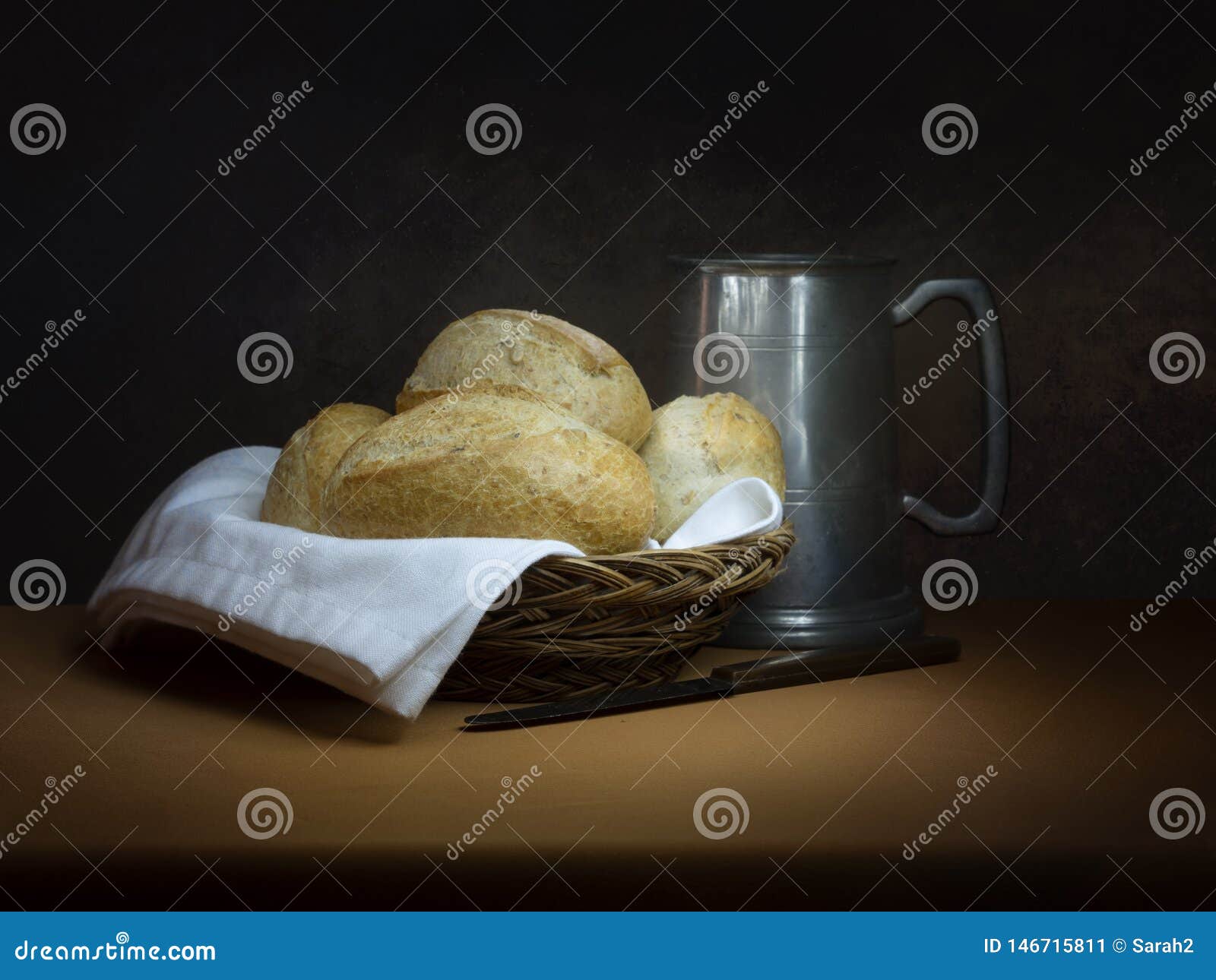 bread and ale, rustic lunch, with old pewter tankard, bread rolls and knife. painting like chiaroscuro still life.