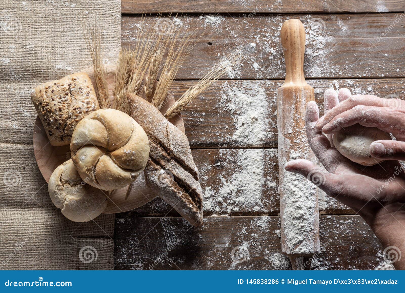 bread with wheat ears and flour on wood board, top view