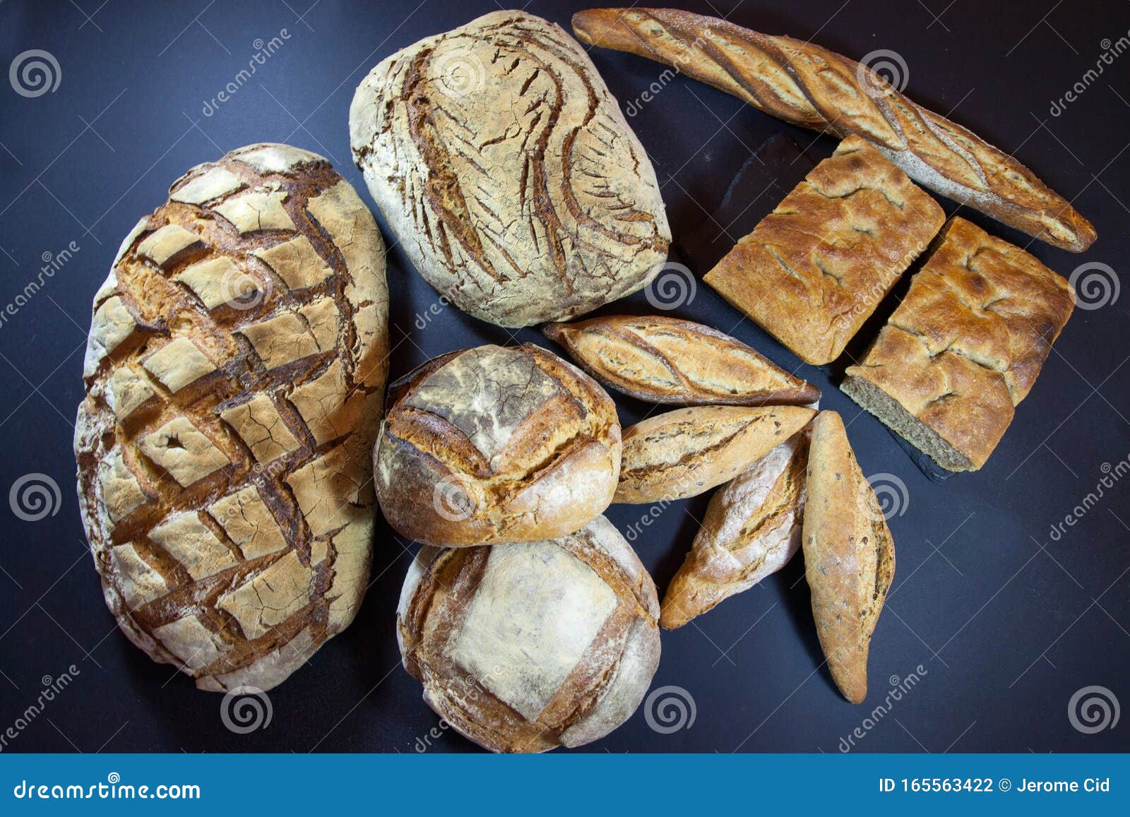various french breads, such as baguette, petits pains and loafs of sourdough, called pain de campagne, on display on a table.