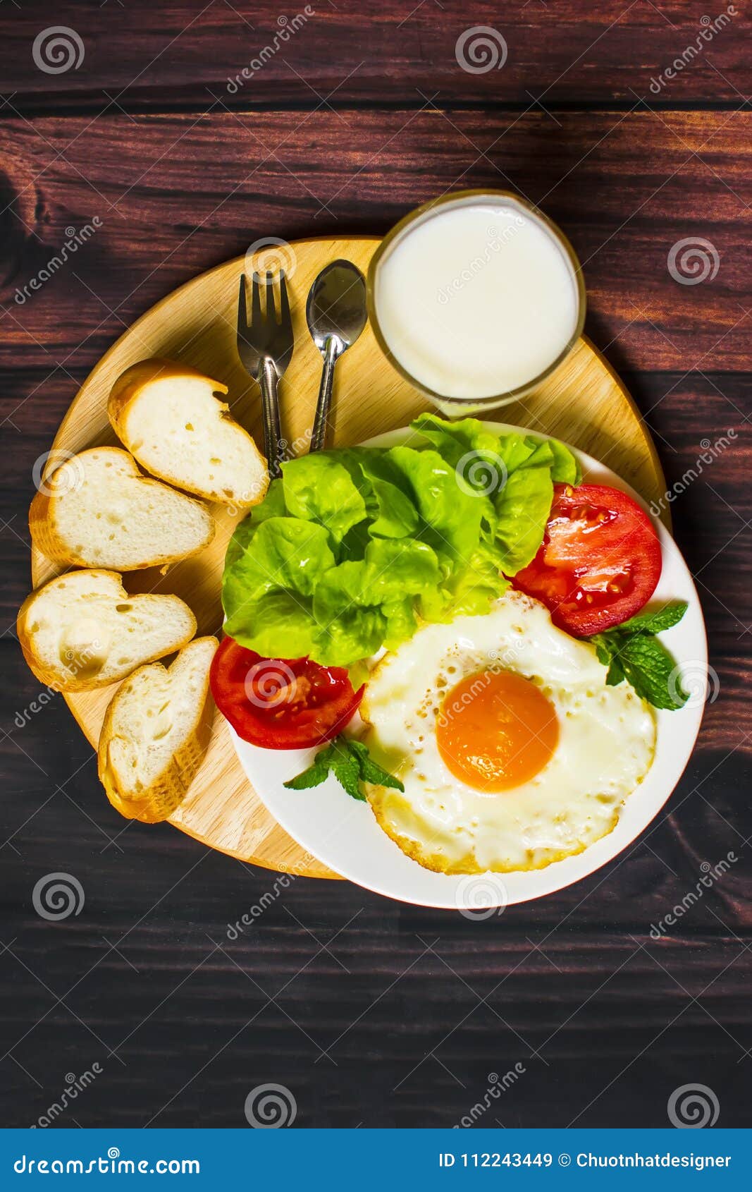 Breakfast with Bread, Fried Eggs, Milk and Vegetables and Fried Tomato