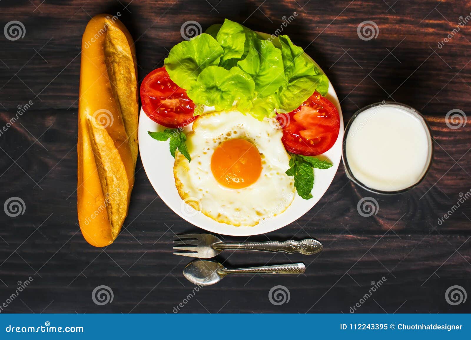 Breakfast with Bread, Fried Eggs, Milk and Vegetables and Fried Tomato