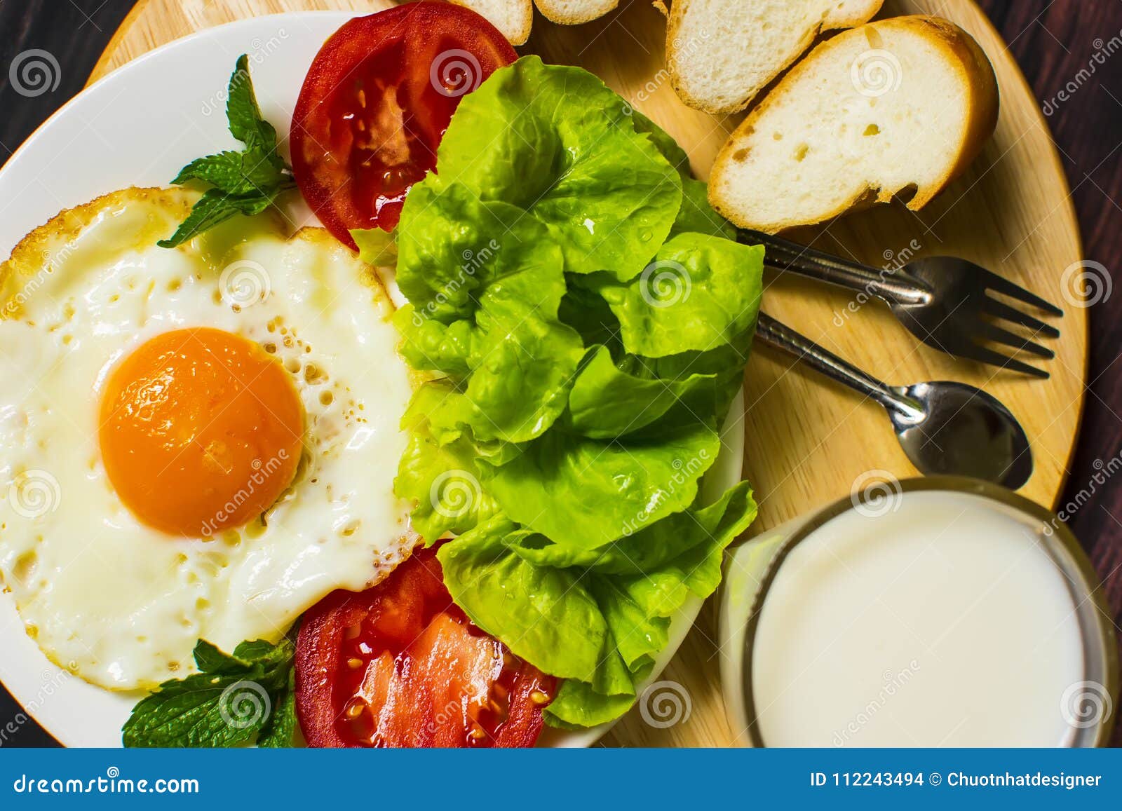 Breakfast with Bread, Fried Eggs, Milk and Vegetables and Fried Tomato