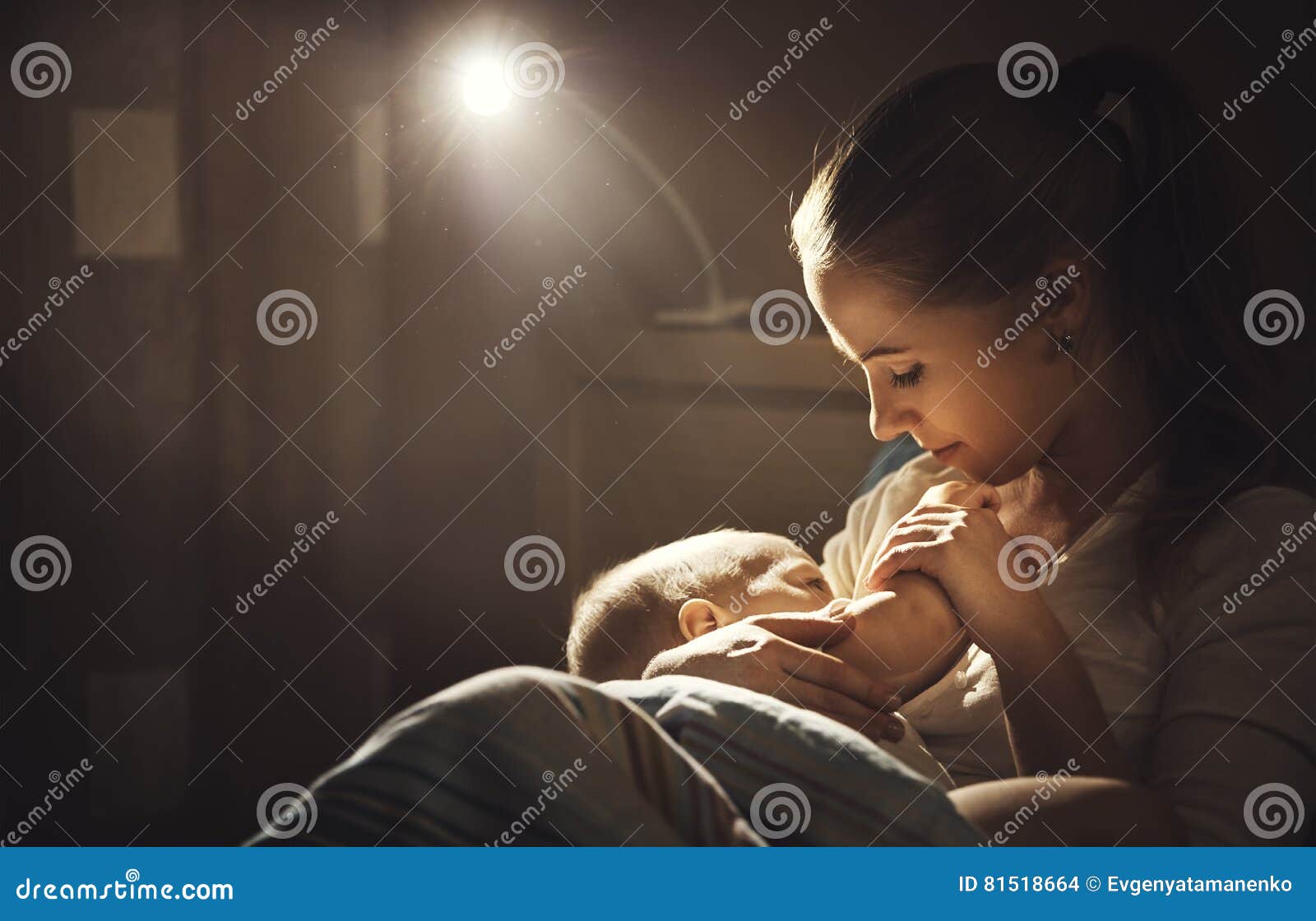 breastfeeding. mother feeding baby breast in bed dark night