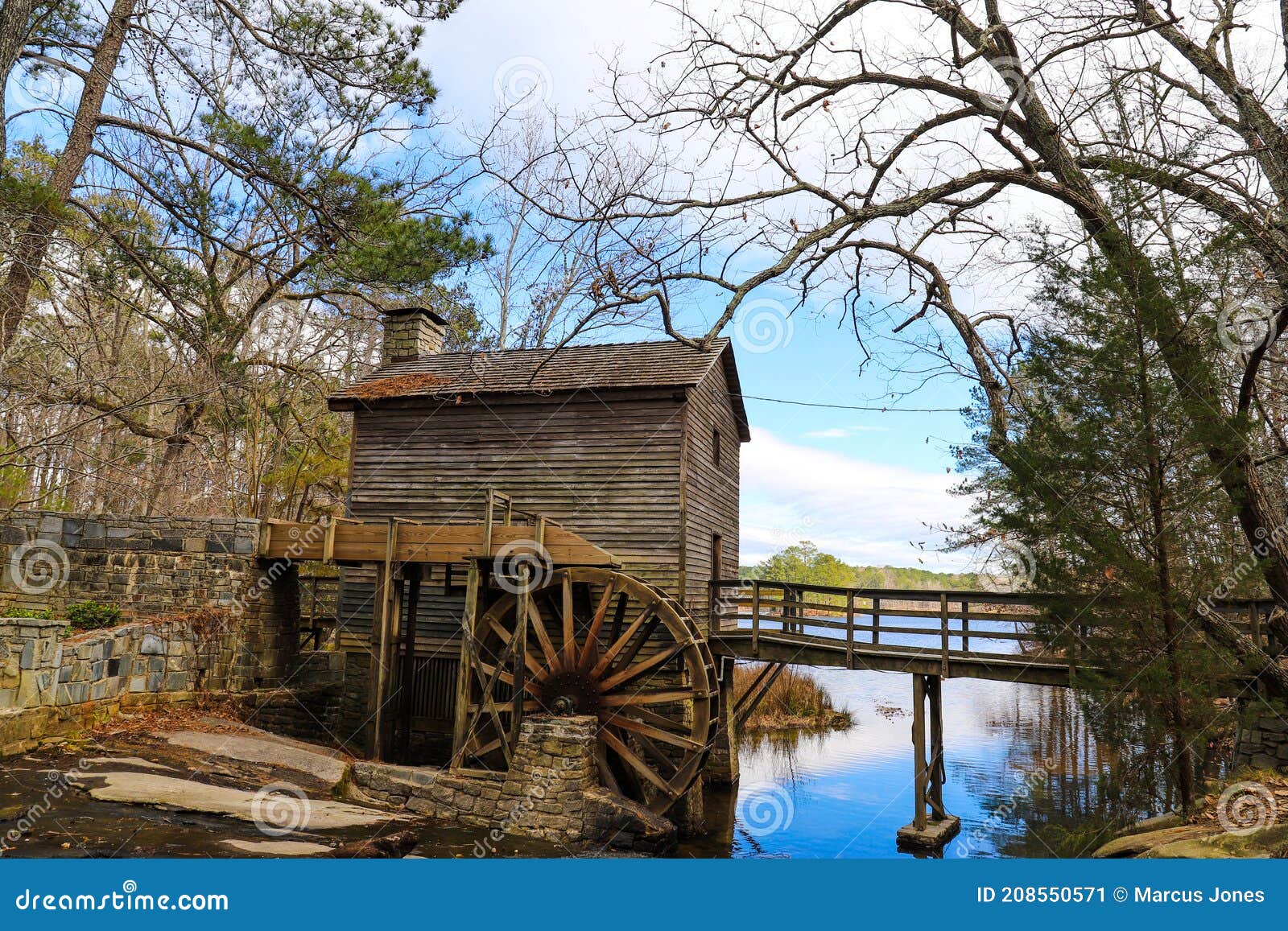 a breathtaking shot of the old wooden grist water mill at stone mountain park with vast blue lake water