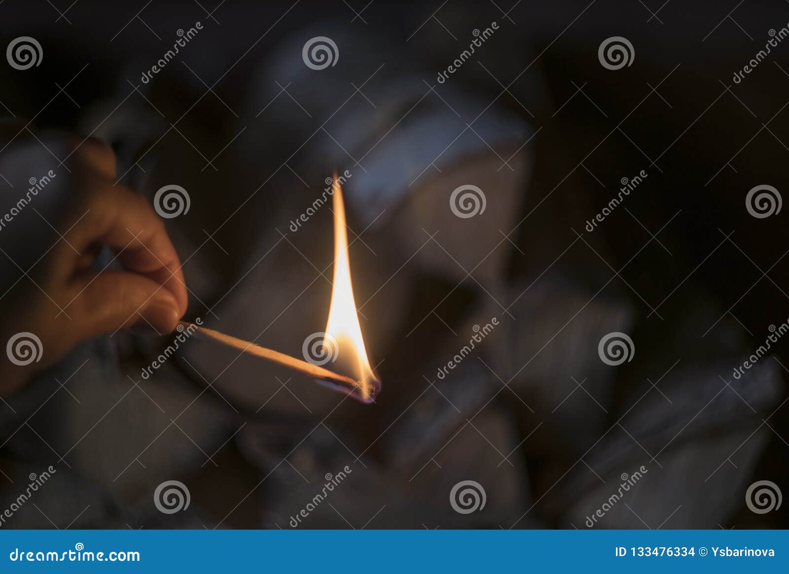 Brennendes Match in der Hand an unscharfem Brennholzhintergrund, an Feuerlandhausstil und an Dorffoto, gemütliche warme Stimmung