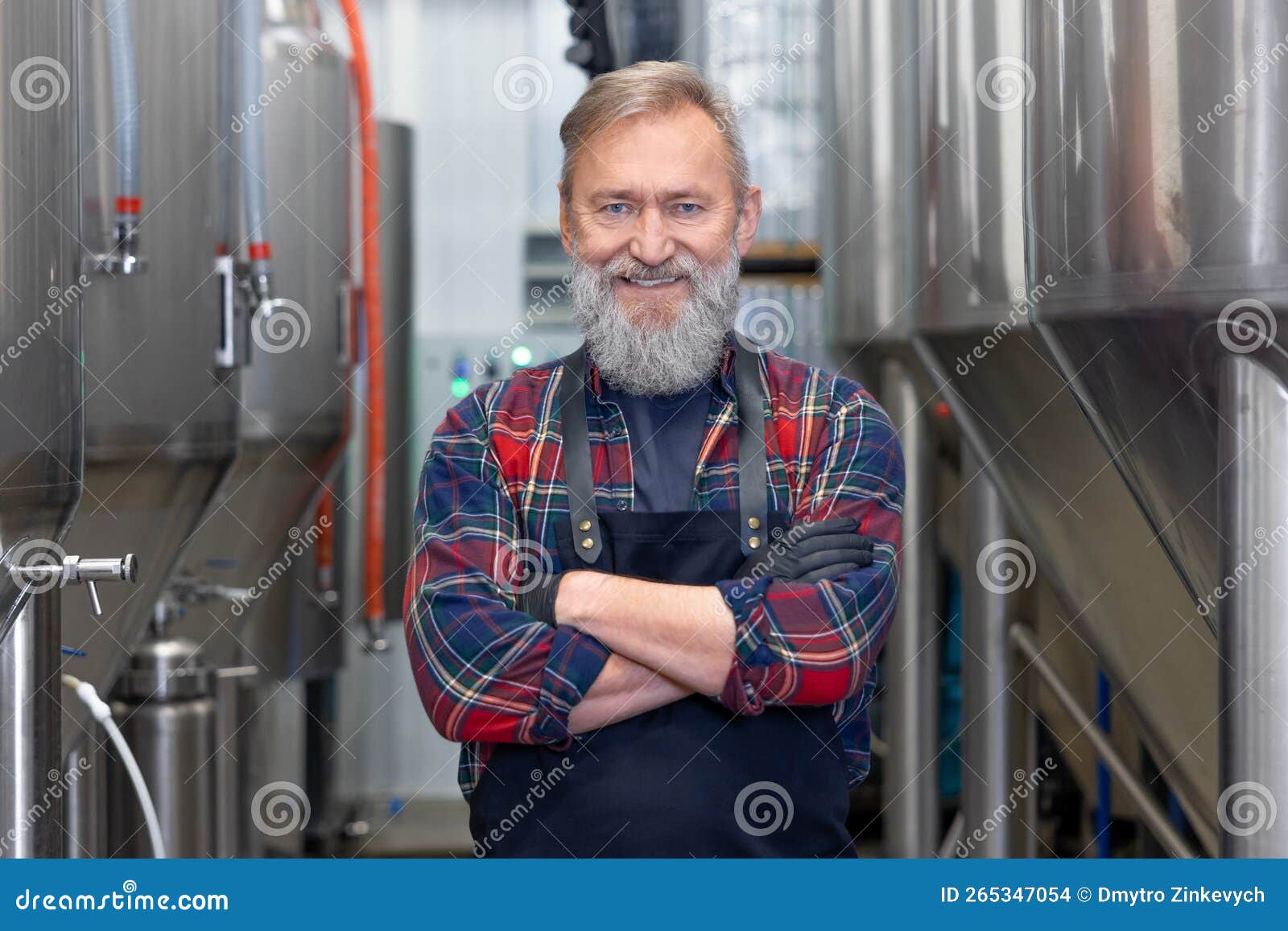 Brewery Worker Standing Near the Metal Tanks and Looking Determined