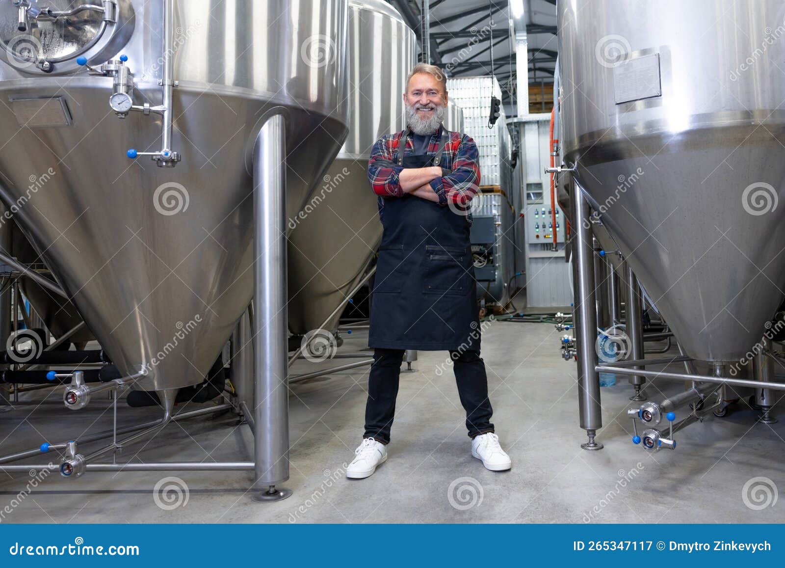 Brewery Worker Standing Near the Metal Tanks and Looking Determined