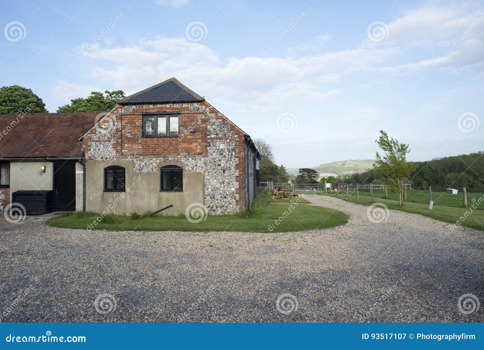 brick barn house and surrounding gravel driveway