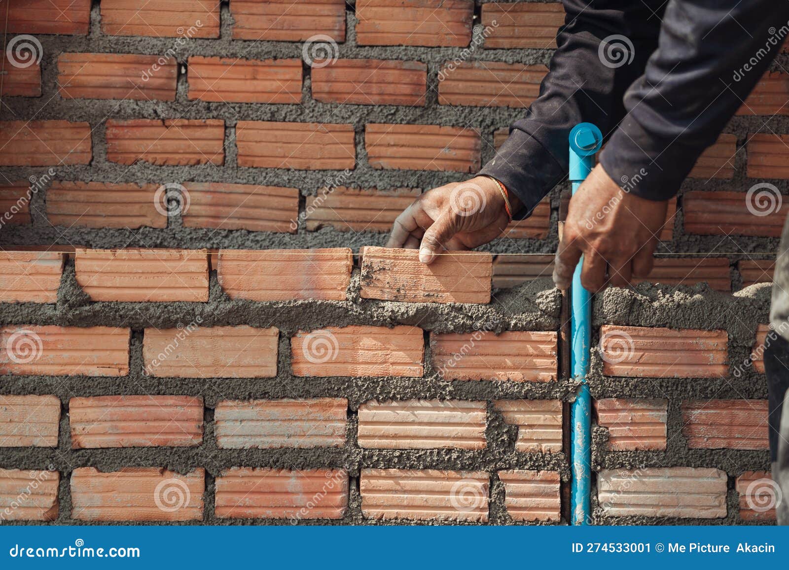 Bricklayer Masonry Installing Red Bricks and PVC Pipe in a New Wall