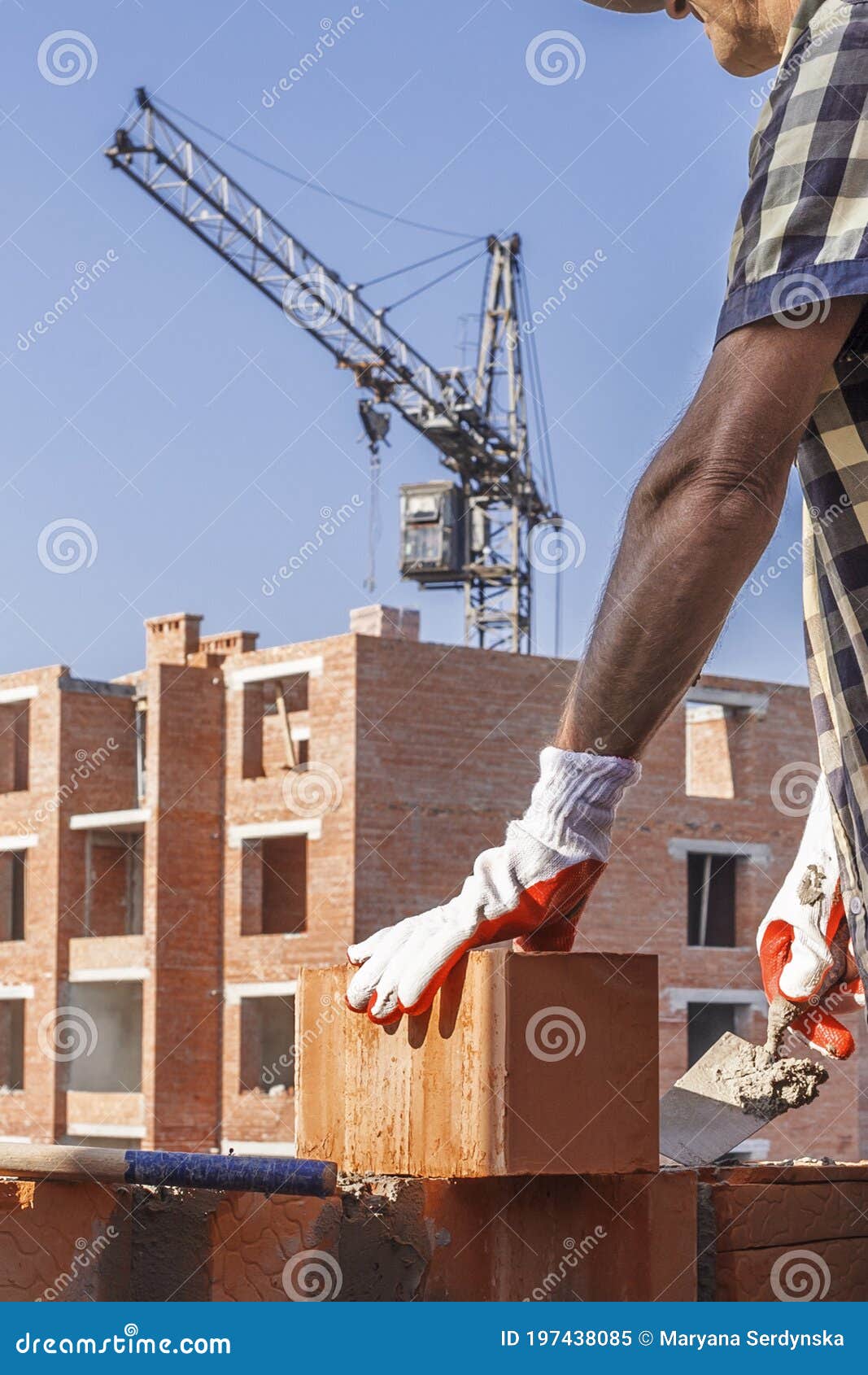 Bricklayer in Protective Gloves with a Trowel Installing a Brick Stock