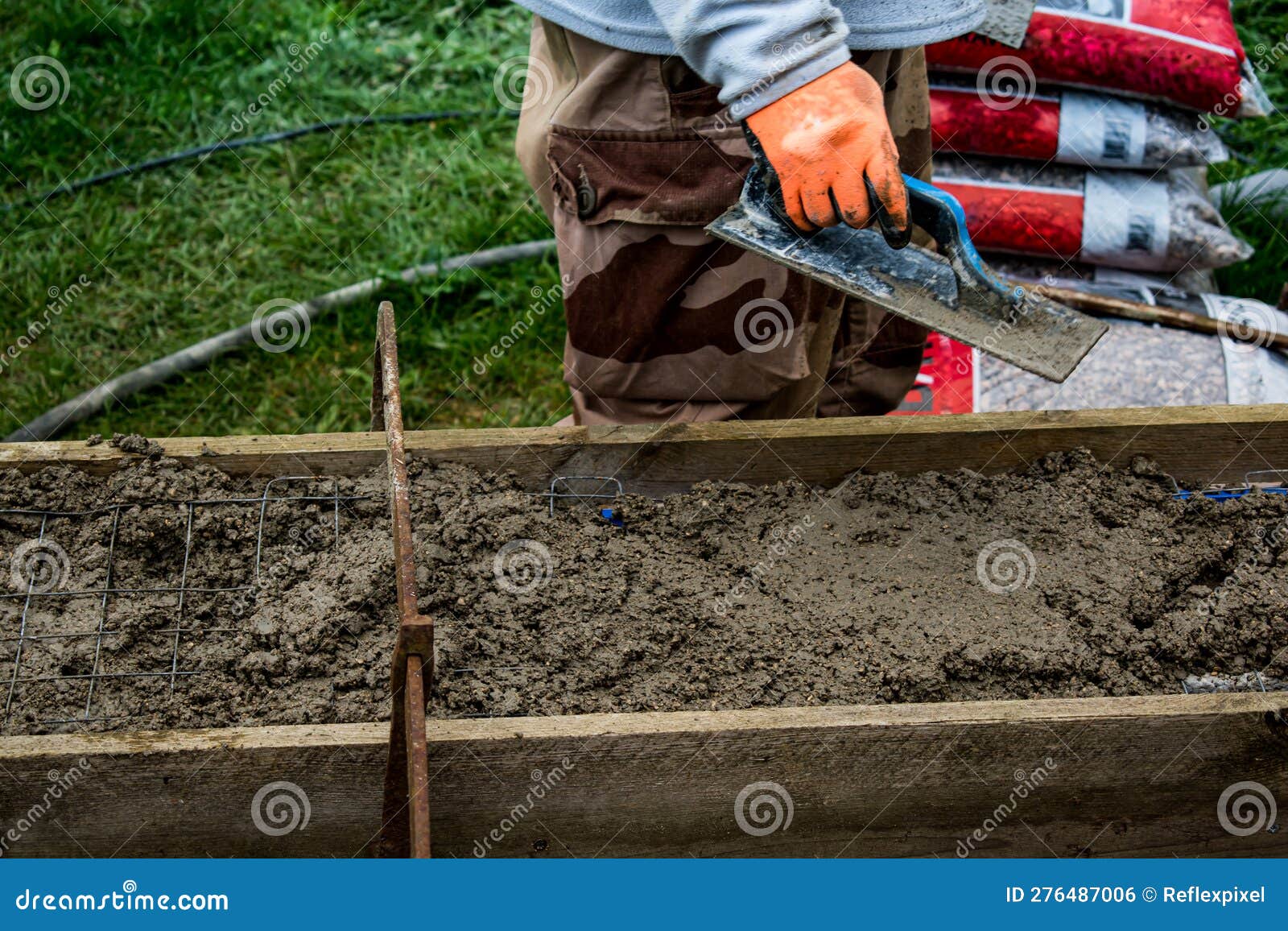 Bricklayer Spreading Concrete with a Trowel and Level To Build a Wall at a Construction Site