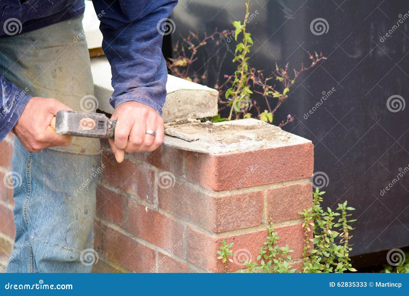 Bricklayer Using Lump Hammer and Bolster To Clear Old Render Stock