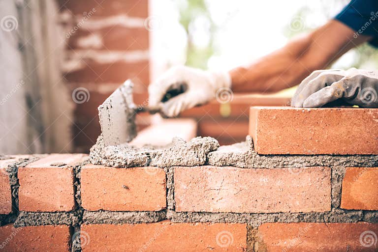 Bricklayer Worker Installing Brick Masonry on Exterior Wall with Trowel