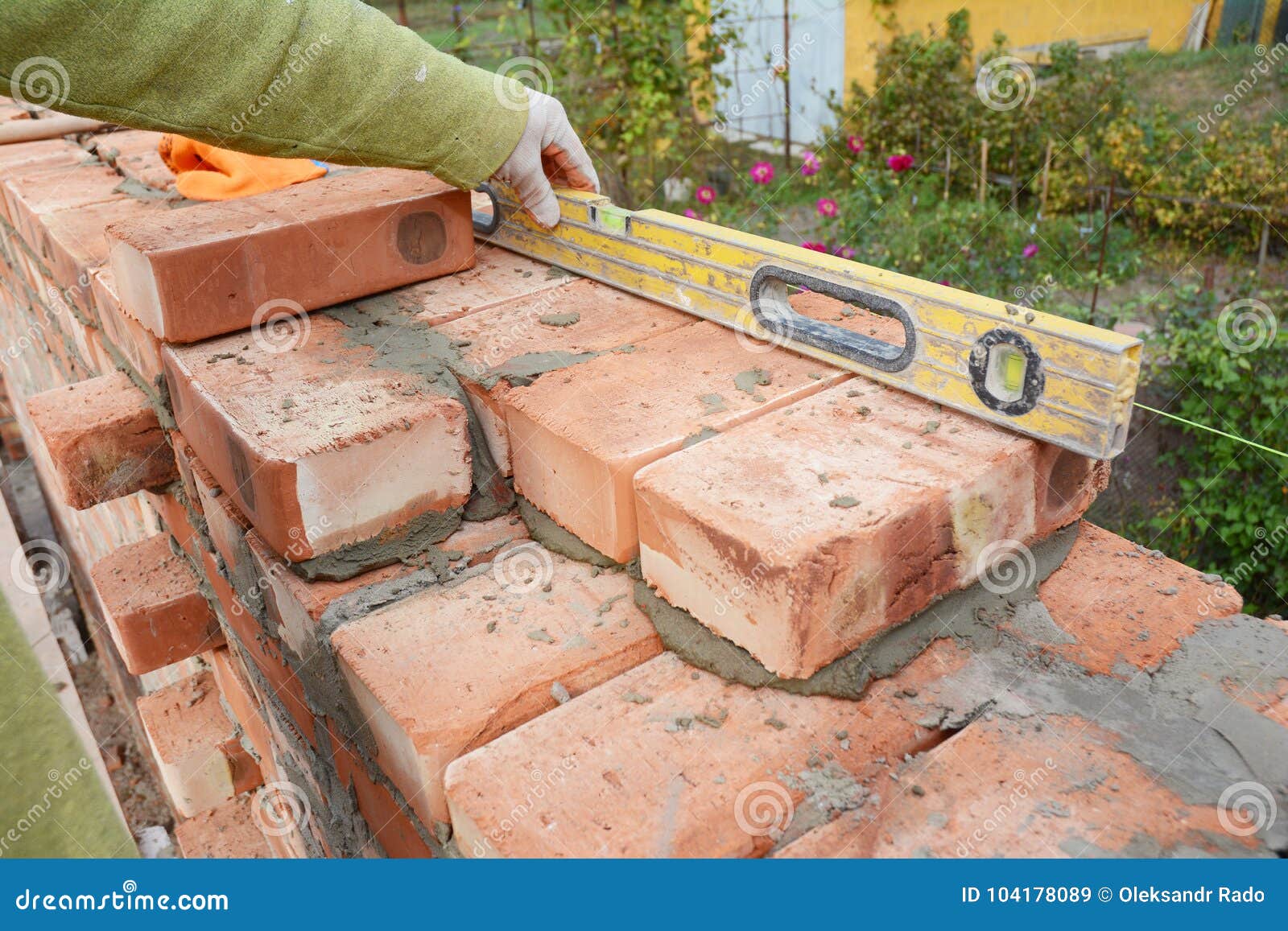 bricklaying, brickwork. close up bricklaying on house cnstruction site. bricklayer using a spirit level to check brick wall o