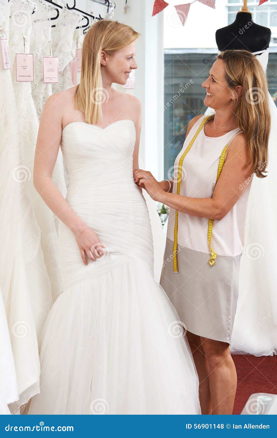 Bride Being Fitted For Wedding  Dress  By Store  Owner  Stock 