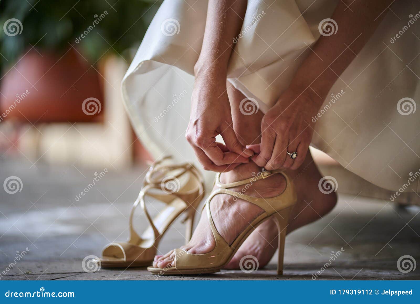 bride in gown putting jimmy choo ivory shoes in a garden previous to bride wearing them for her wedding