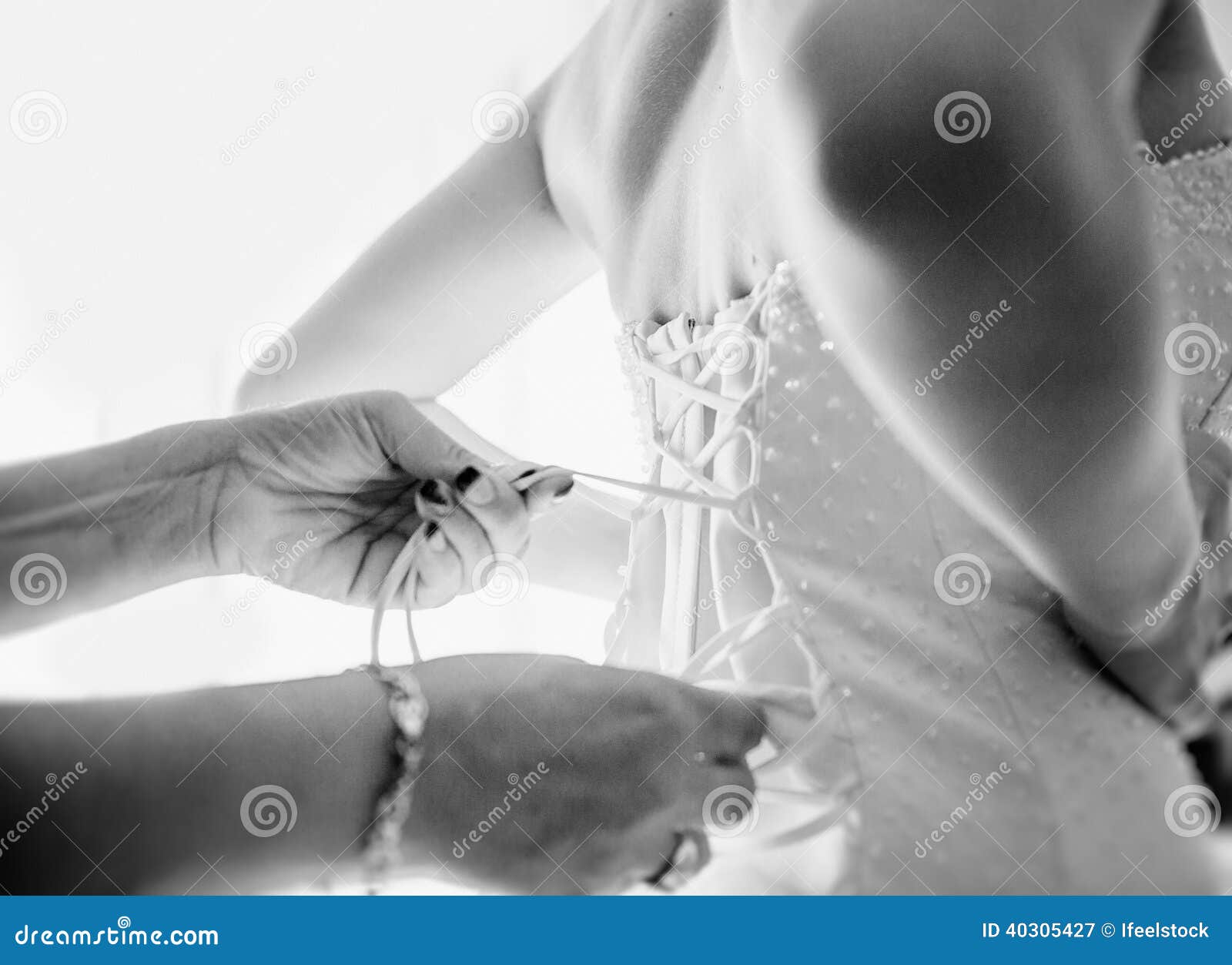 bride having helped by her mother to fix dress