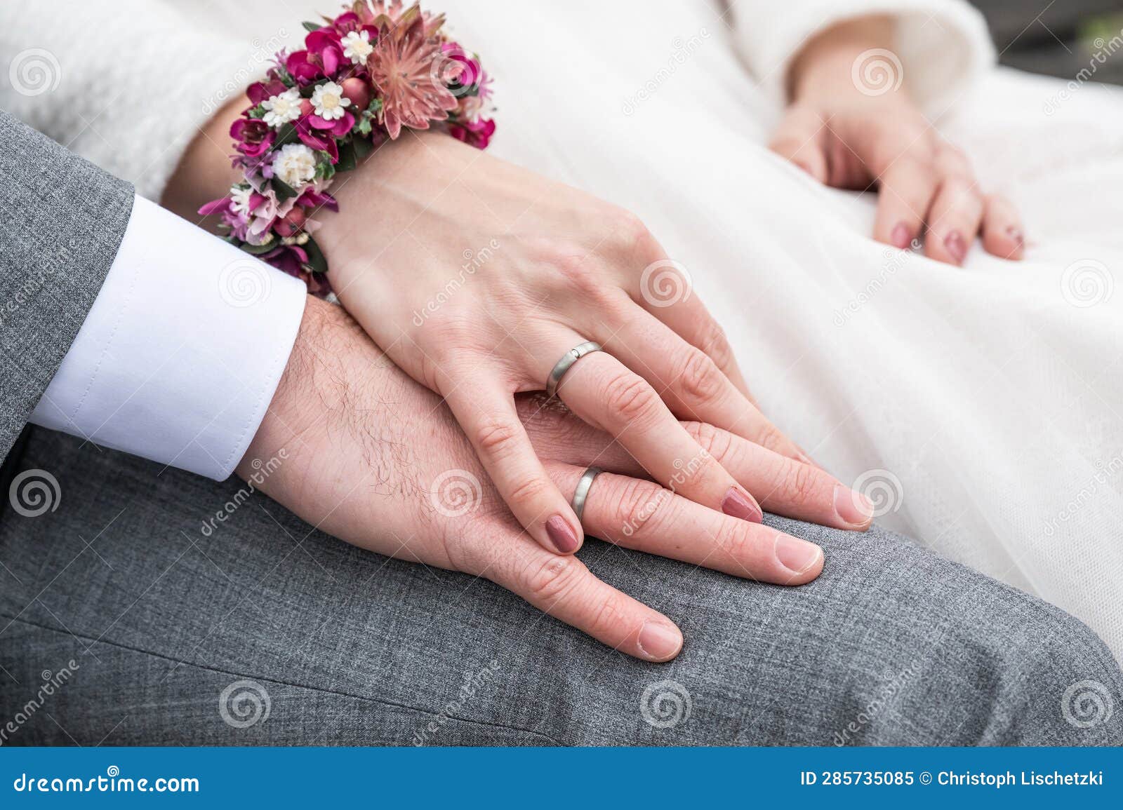 Bride Holding Groom Hand with Wedding Rings Sitting on Bench Stock