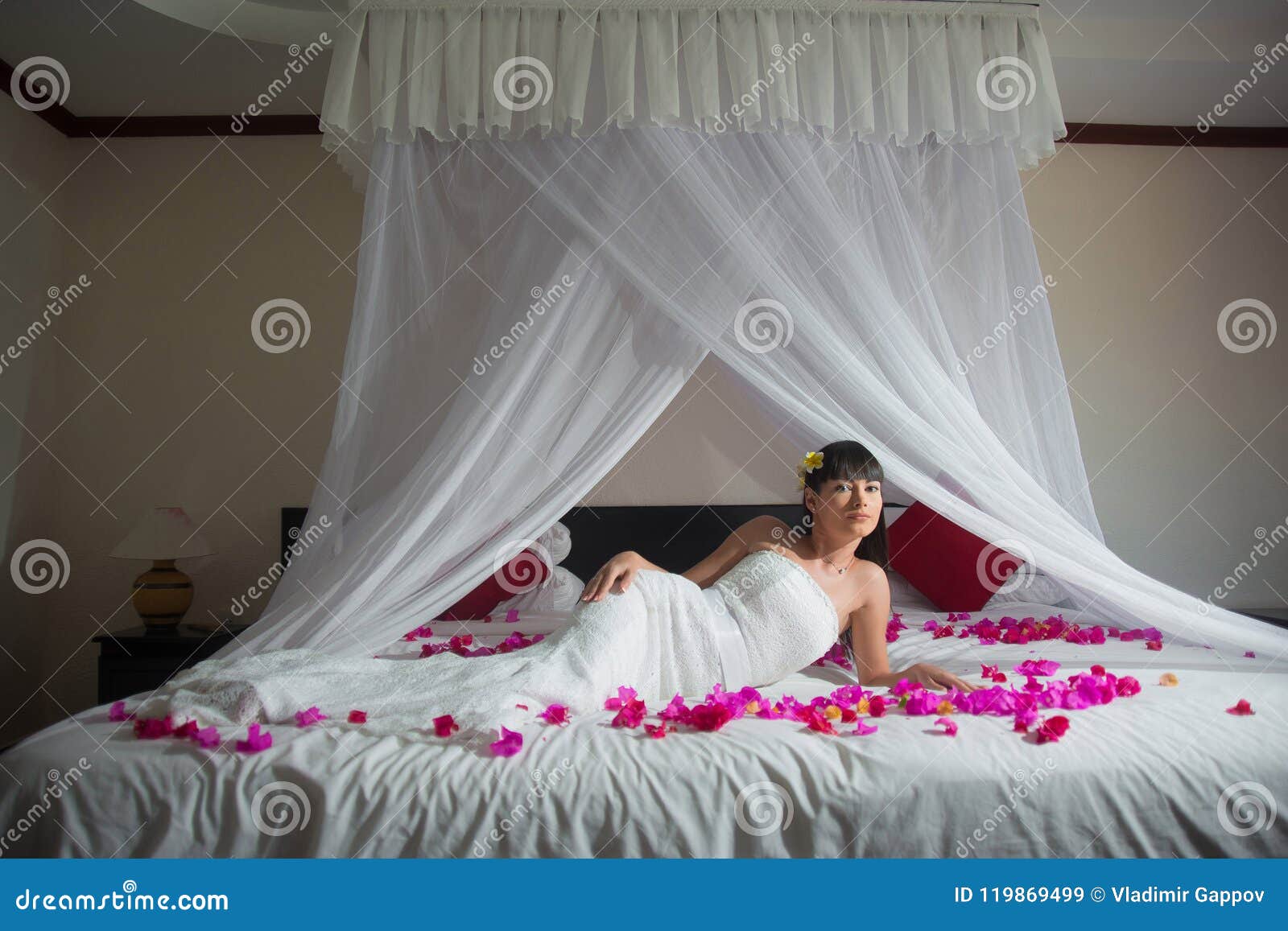 Bride is Lying on a White Bed in Rose Petals in the Hotel Stock Image