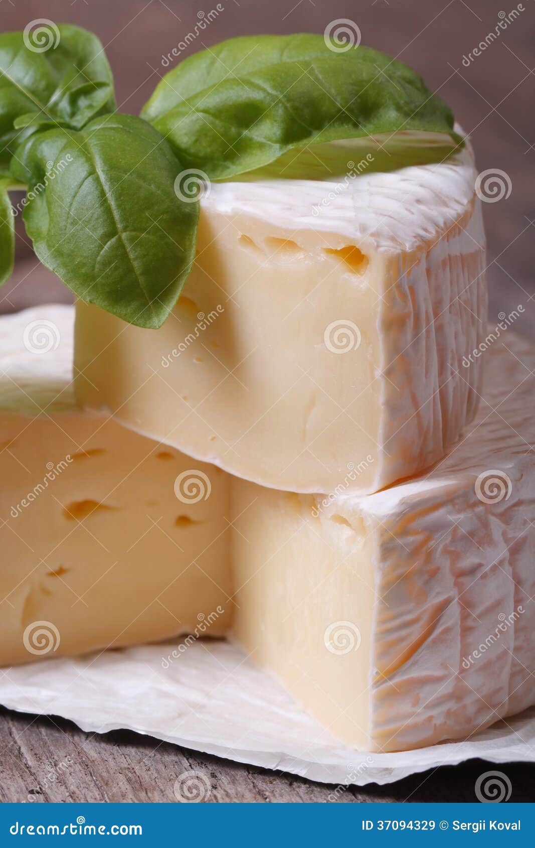 Brie Cheese on Wooden Table with Basil Macro. Vertical Stock Image