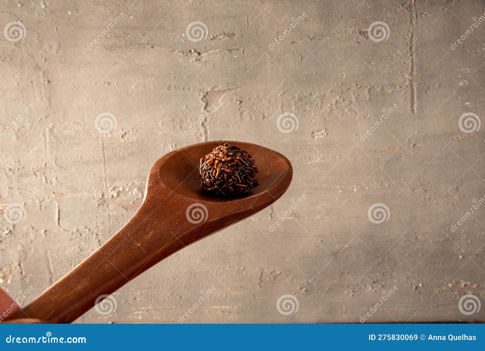 brigadeiro in wooden spoon on gray background