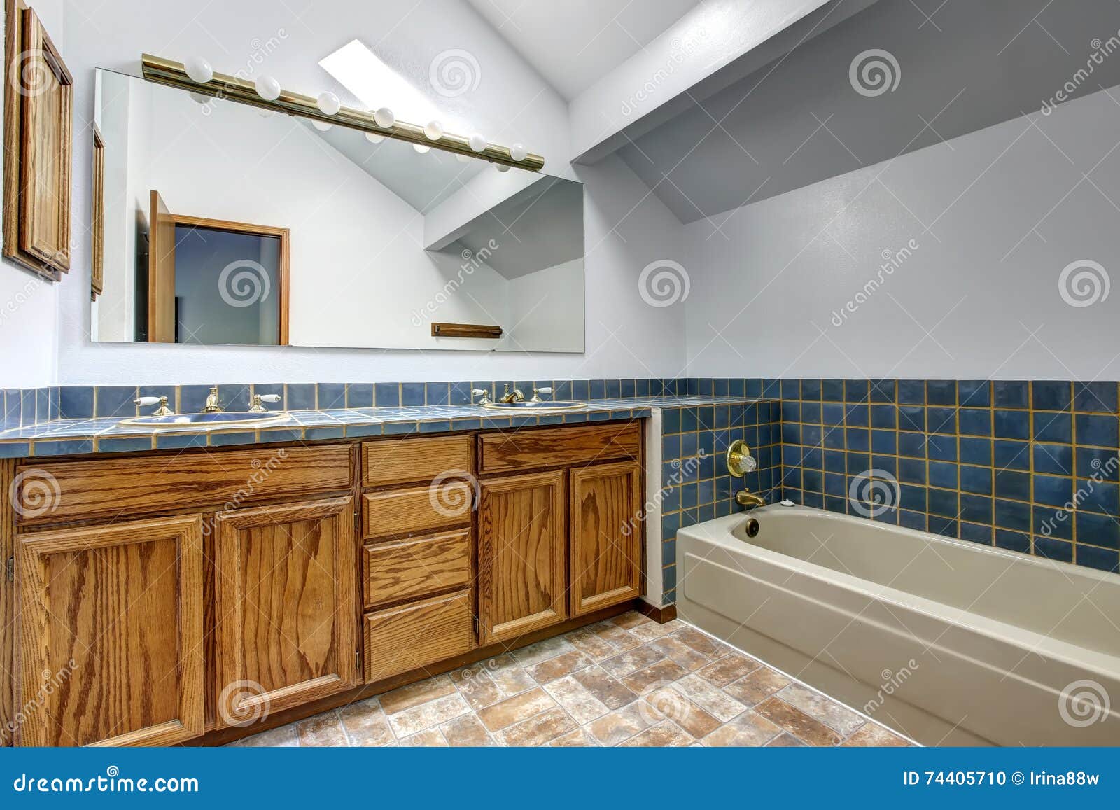 Bright Bathroom With Vaulted Ceiling And Blue Tile Wall Trim Stock