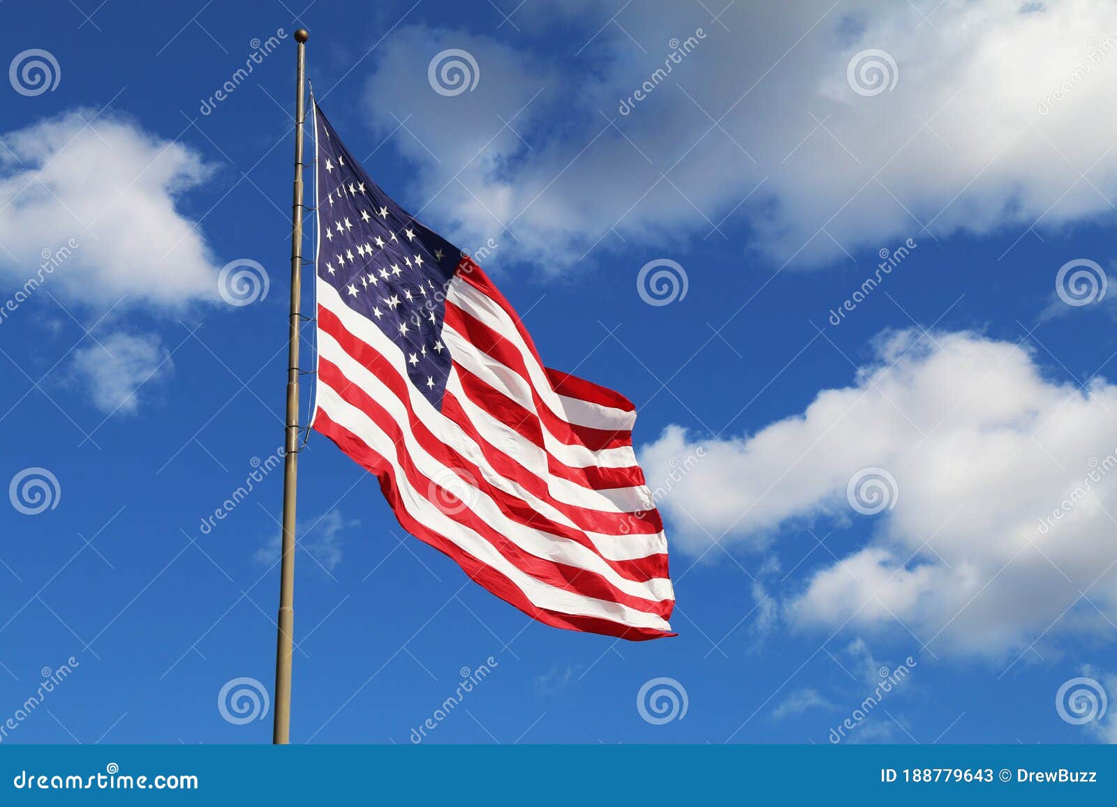 bright flowing waving american flag sunny day white clouds. A bright flowing waving american flag on a sunny day with a few white clouds