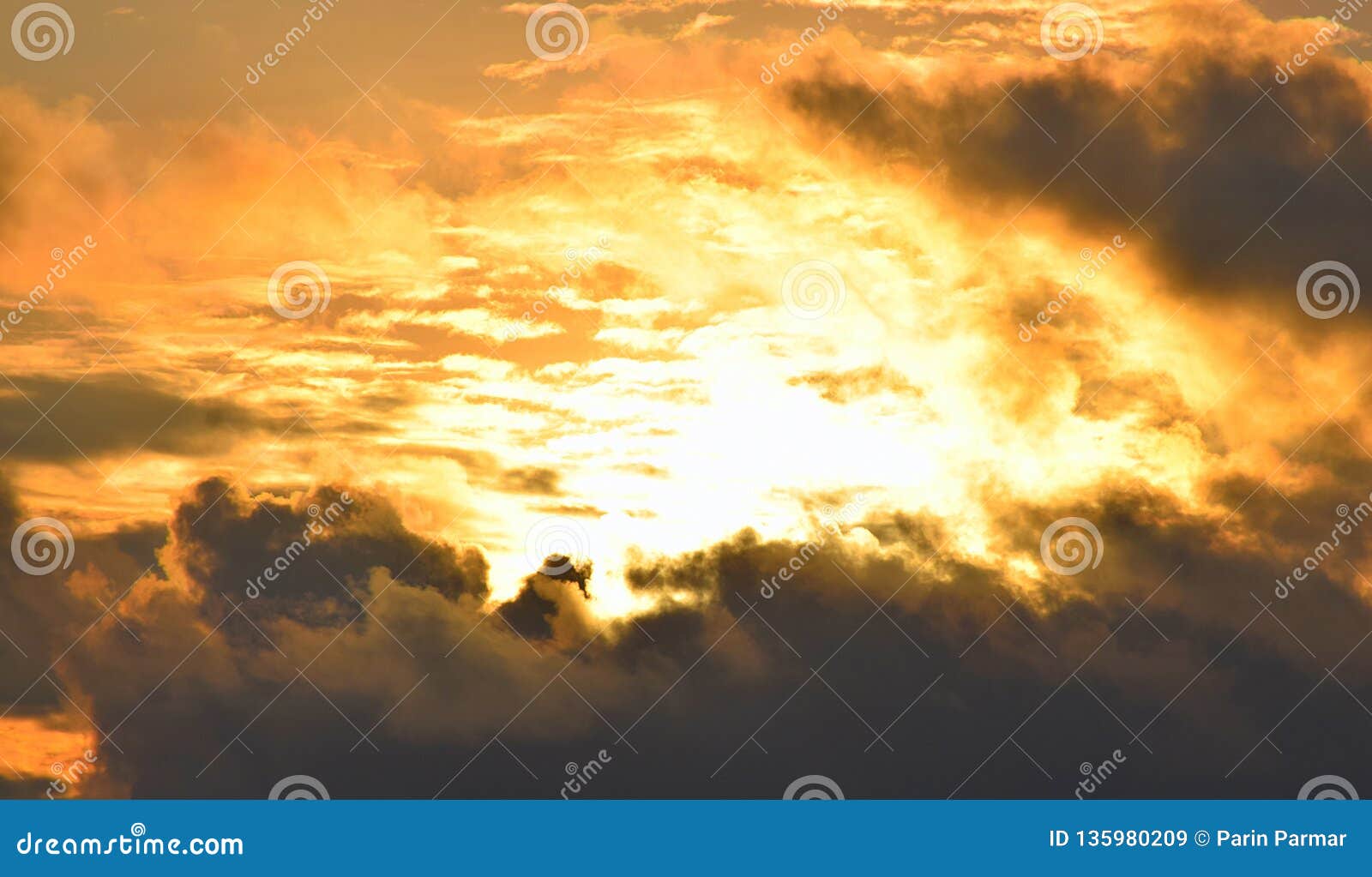 bright golden yellow orange sunlight from dark grey clouds in sky - warm skyscape - heat and solar energy