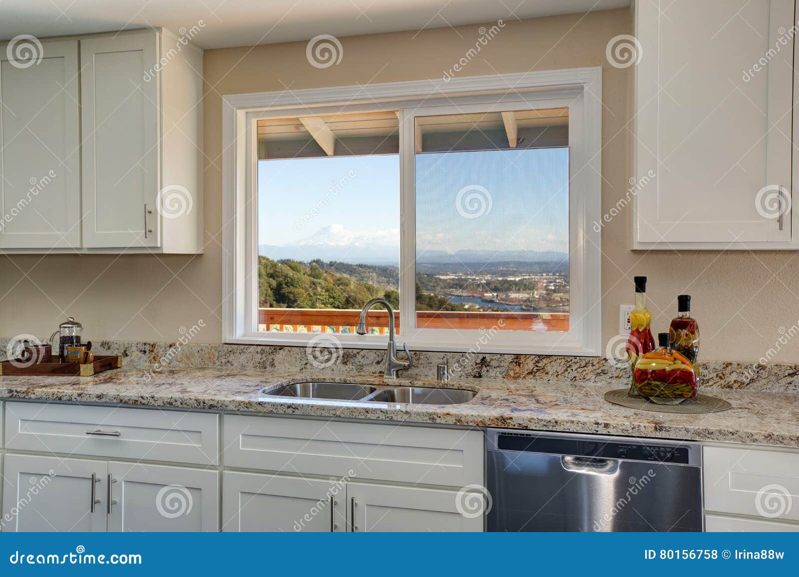 Bright Interior Of Kitchen With White Cabinets And Granite