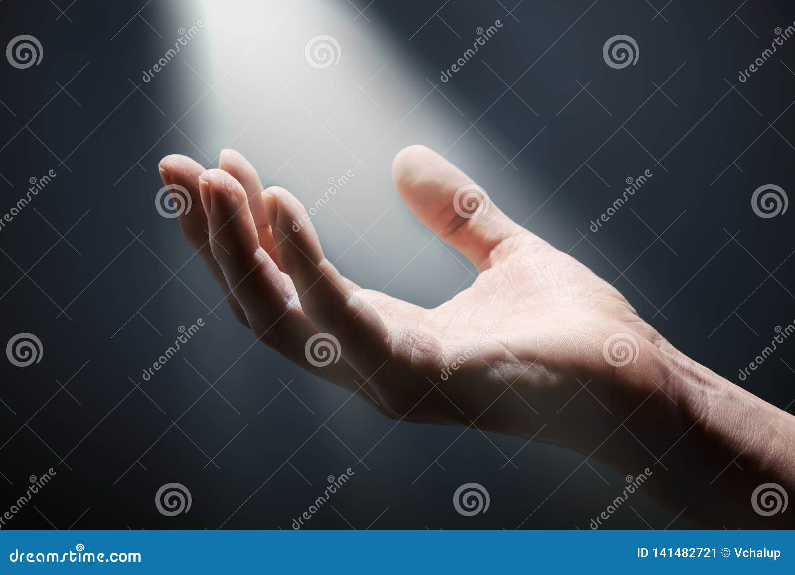 bright light rays shihing on man`s hand in darkness.
