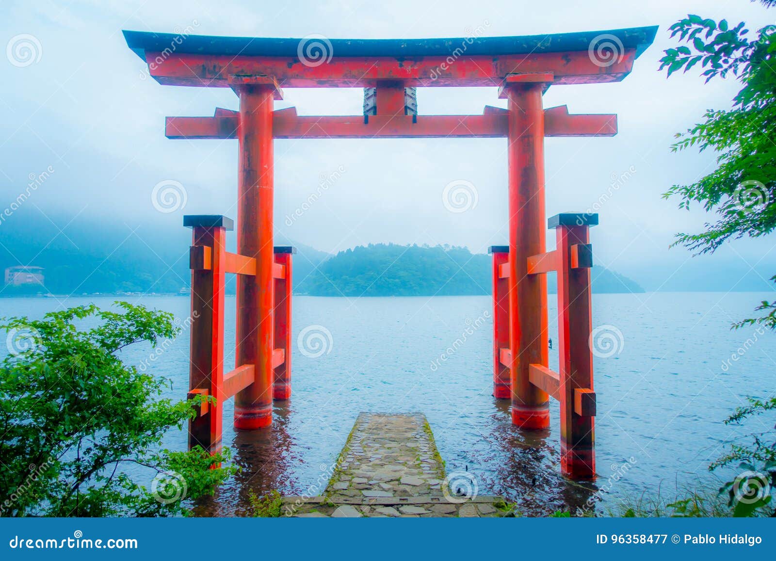 bright red torii gate submerged in the waters of ashi lake, caldera with mountains on the background. hakone shrine, kanagawa pref
