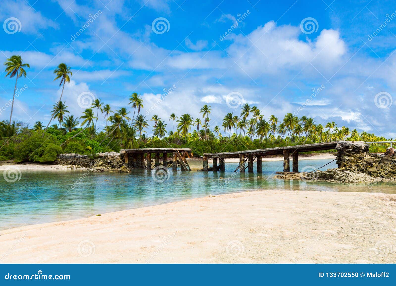 broken bridge under palm trees between islets over lagoon, north tarawa atoll, kiribati, micronesia, gilbert islands, oceania,