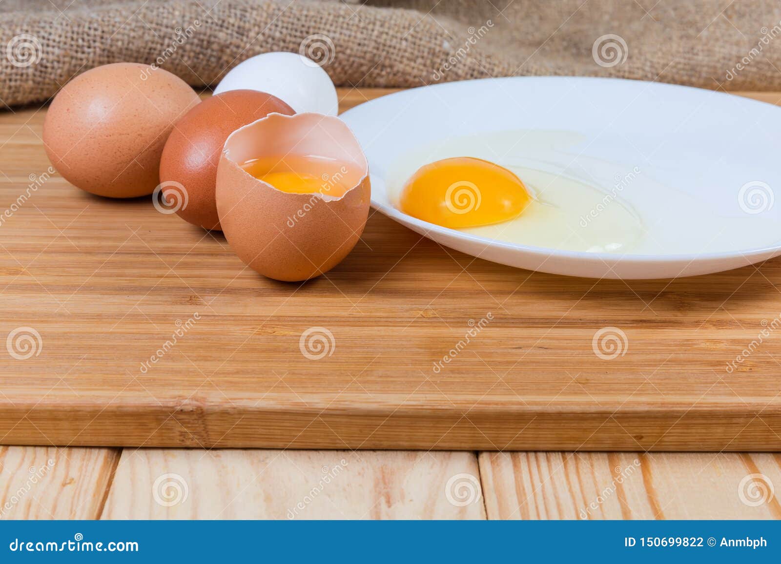 Broken and Whole Eggs on Cutting Board on Rustic Table Stock Photo