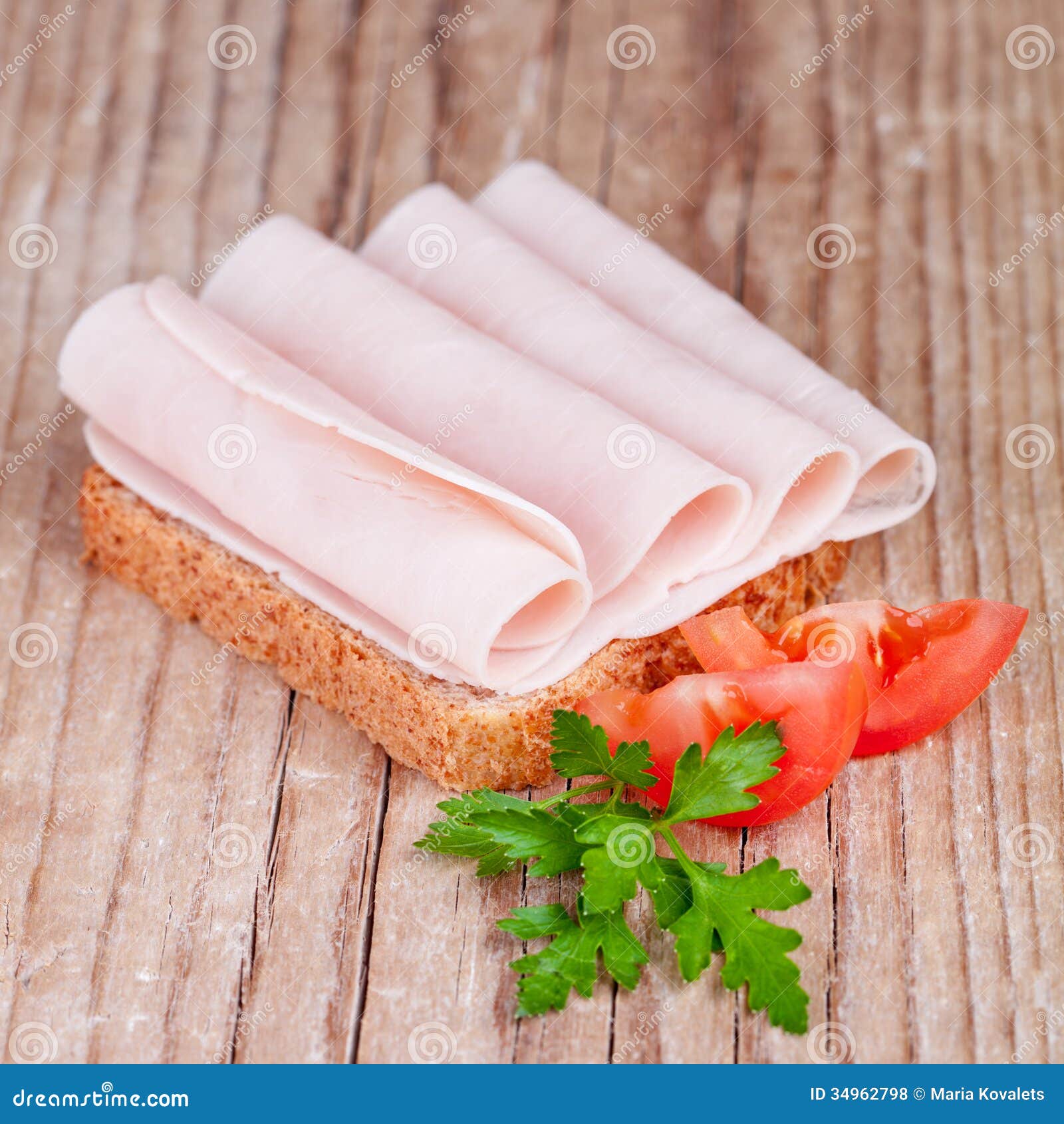 Brood met gesneden ham, verse tomaten en peterselie op rustieke houten achtergrond