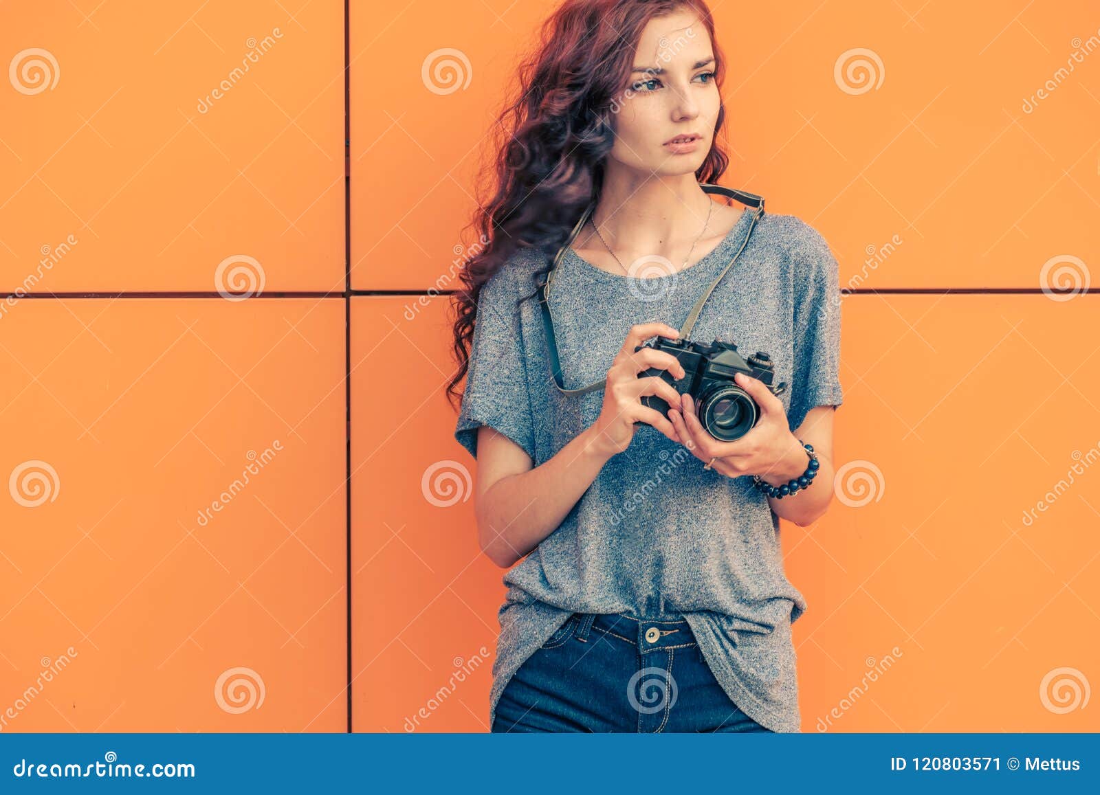 broody hipster girl photographer looking away with vintage film camera in her hands