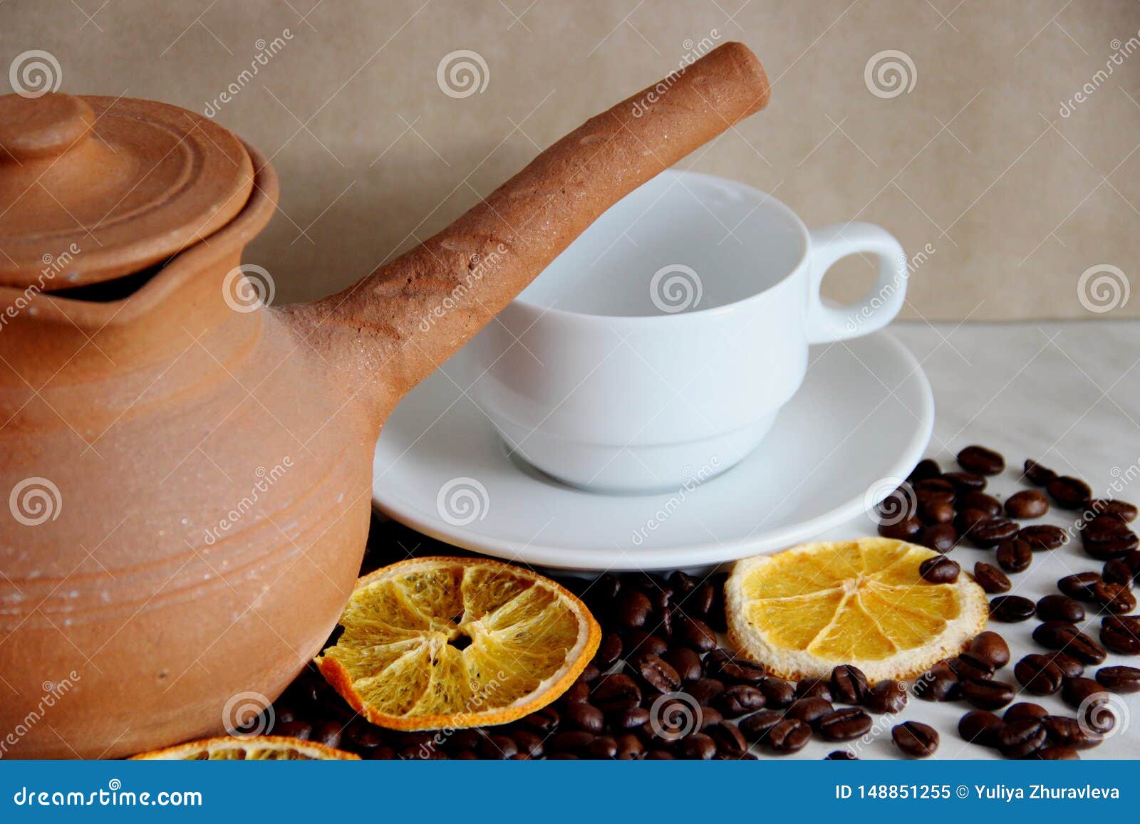 brown clay dishes, white clean Cup and saucer, roasted coffee beans and dried orange on the table, selective focus, close-up