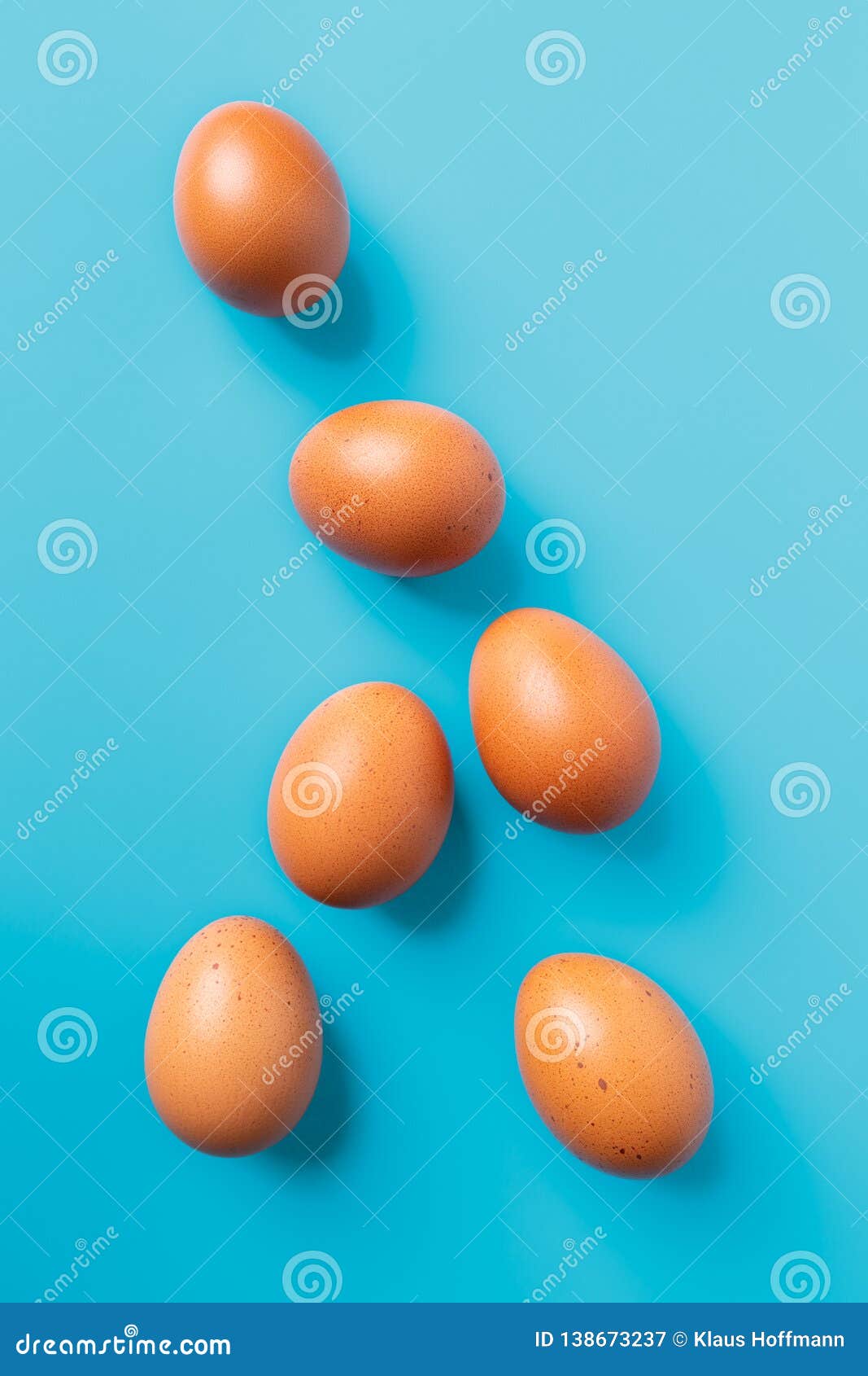 Six brown eggs on blue turquoise background, top view with copy space