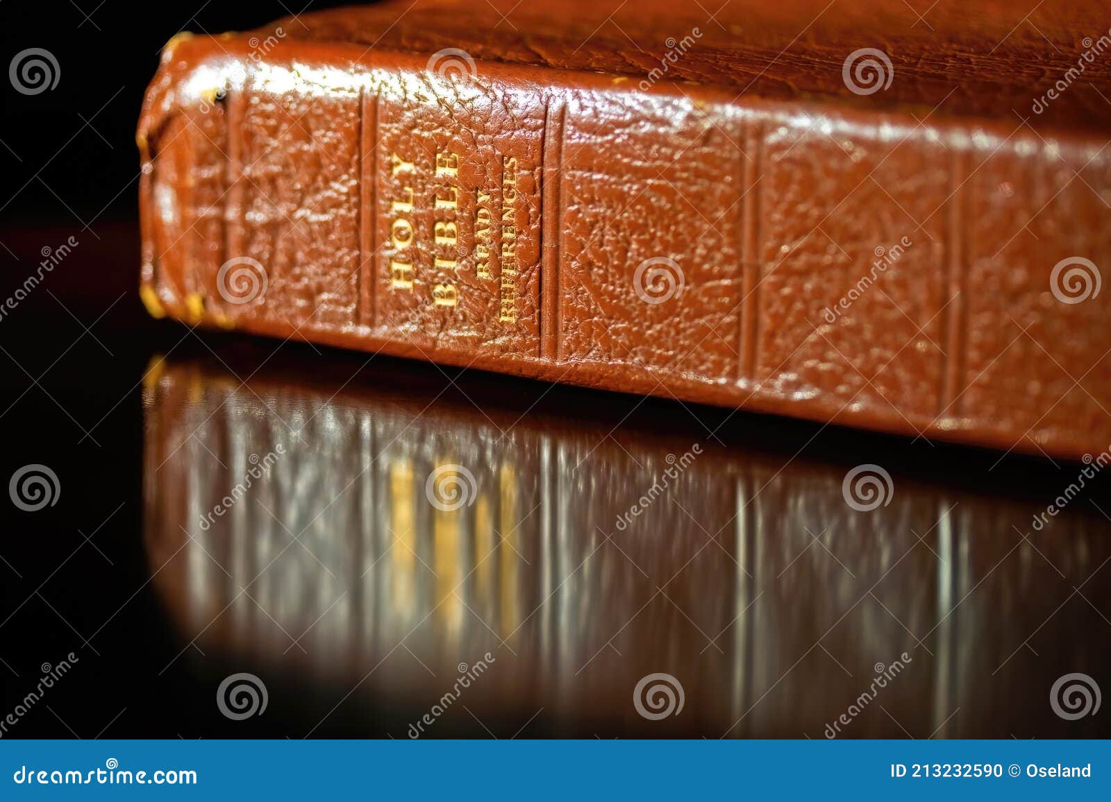 brown leather holy bible with reflection in table top.