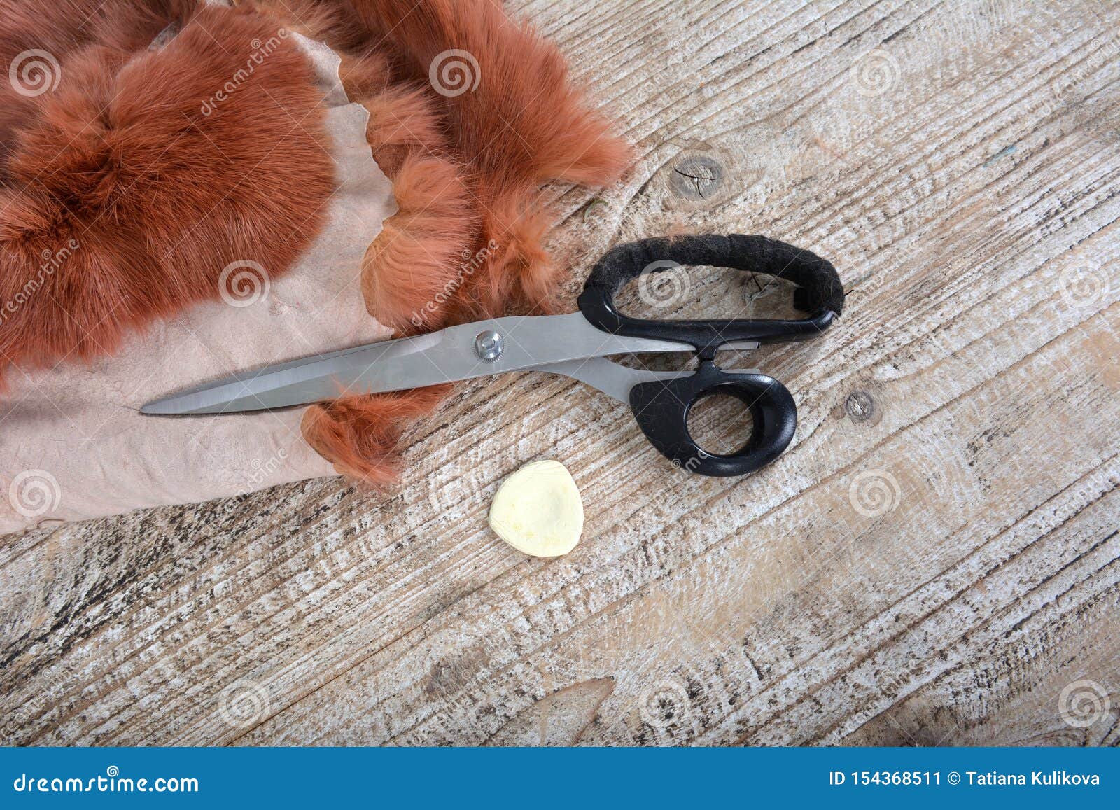 Brown Rabbit Fur for Sewing, Scissors and Chalk on Wooden Background