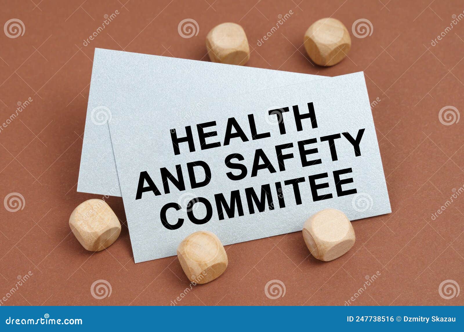 on a brown surface, wooden cubes and a business card with the inscription - health and safety commitee