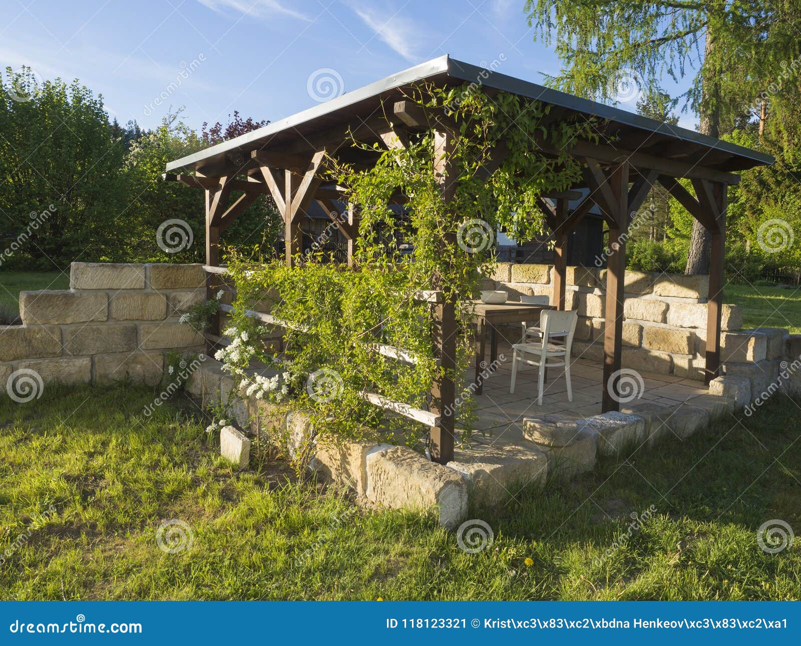 brown tiber wooden gazebo or pergola with climbing plants and fl