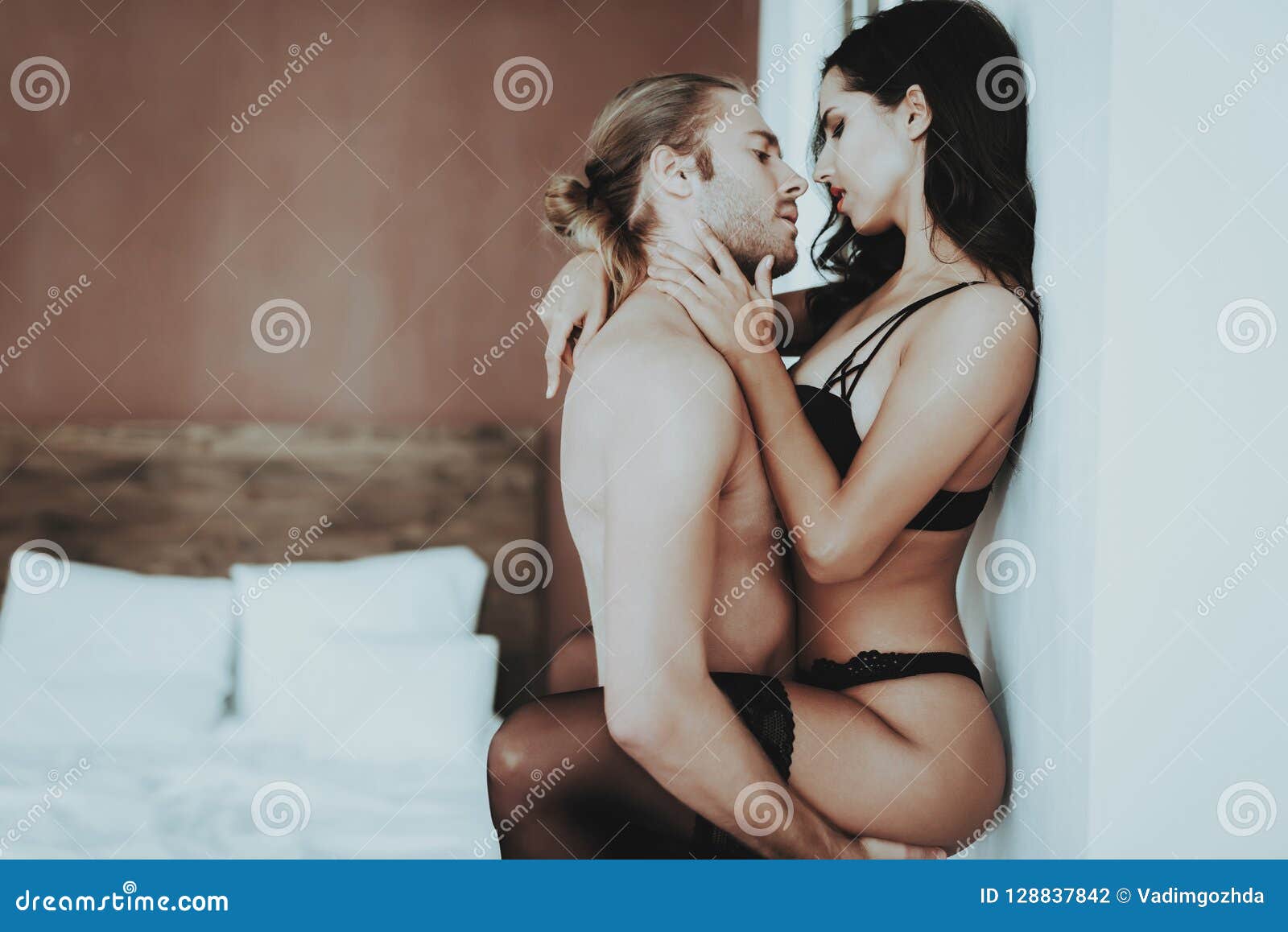 Passionate Man Holding Woman in Lingerie Near Wall Stock Photo pic photo picture