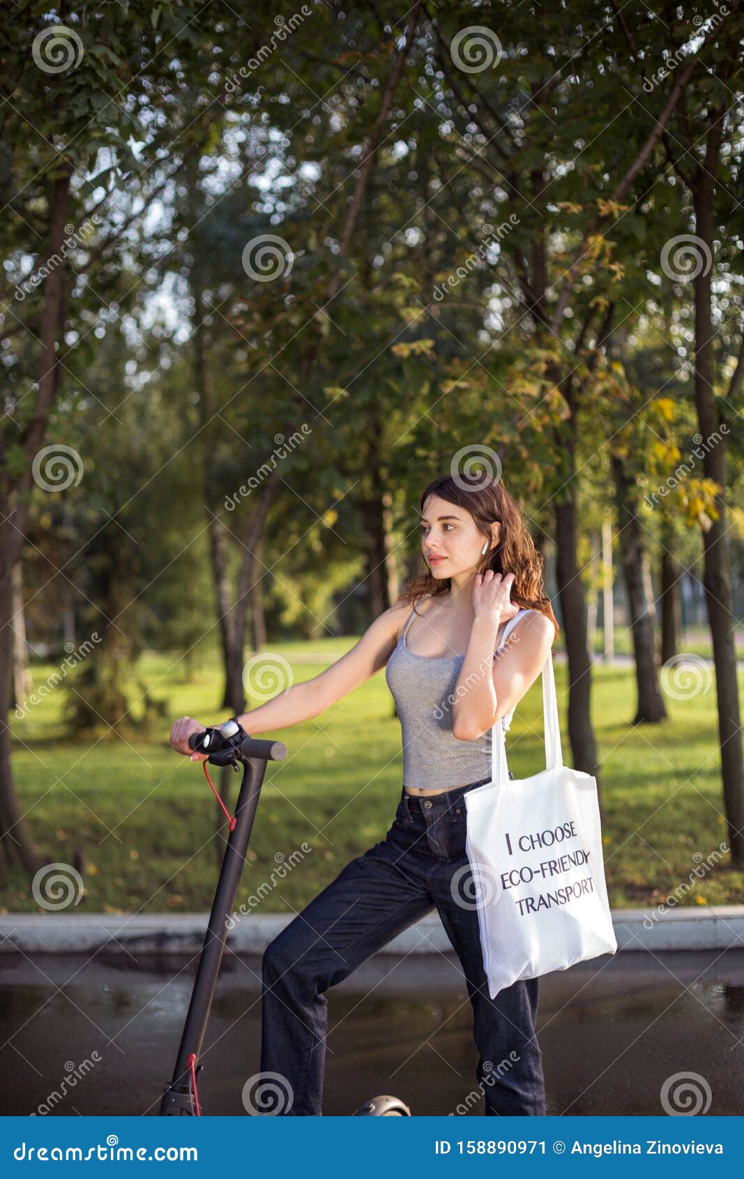 Brunette Girl Riding a Scooter with a Bag on His Shoulder in the Park ...