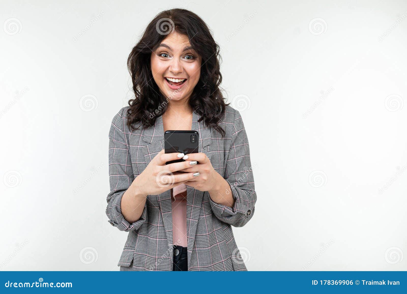 brunette girl smilingly looks into the smartphone display on a white studio background